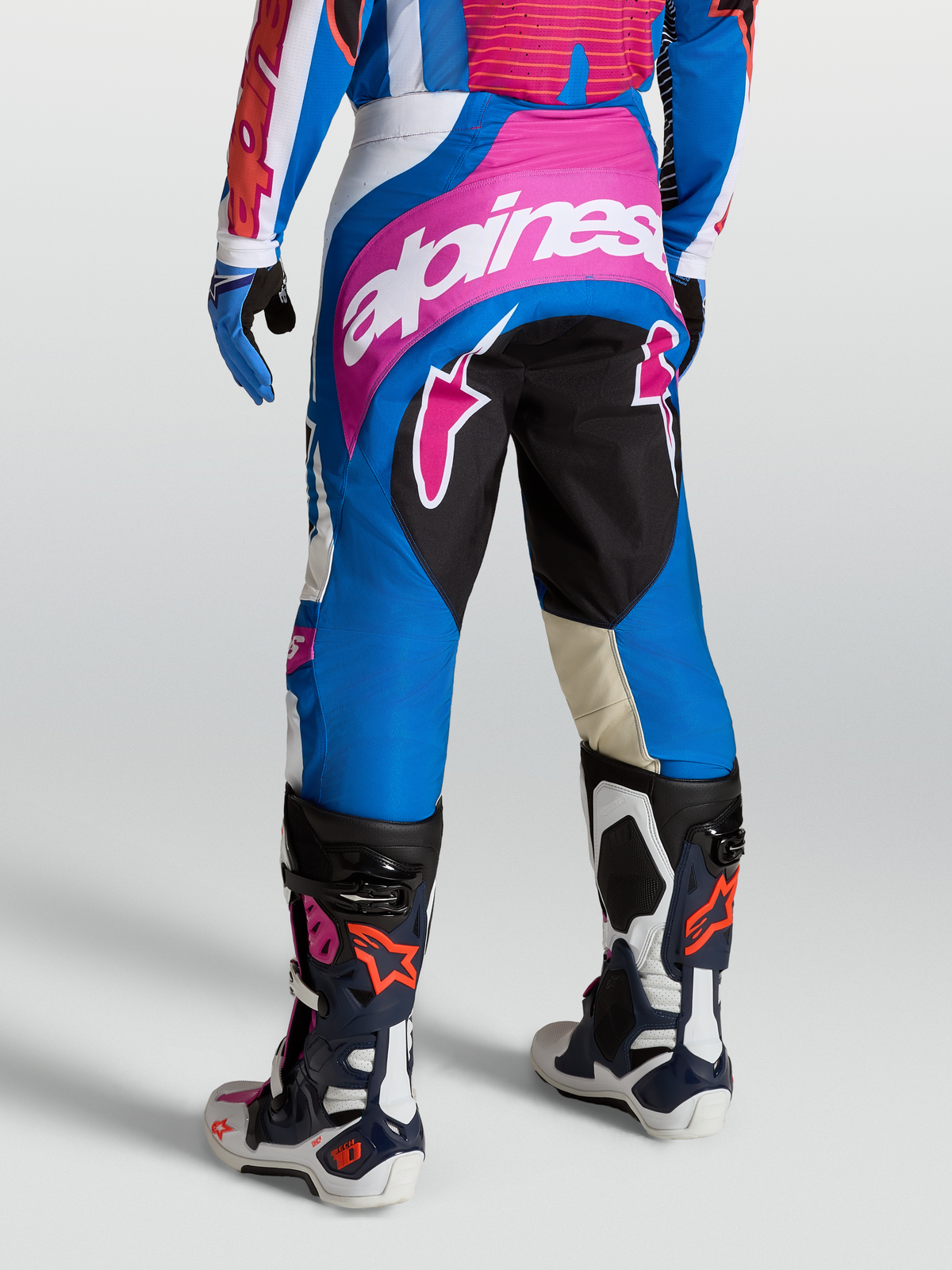 Alpinestars Techstar Maven Hose, Motocross-Hosen für Herren, Blau und Pink, athletische Rennpassform mit verstärktem Sitzbereich, getragen mit Tech-Air kompatibler Racing-Ausrüstung und Stiefeln.