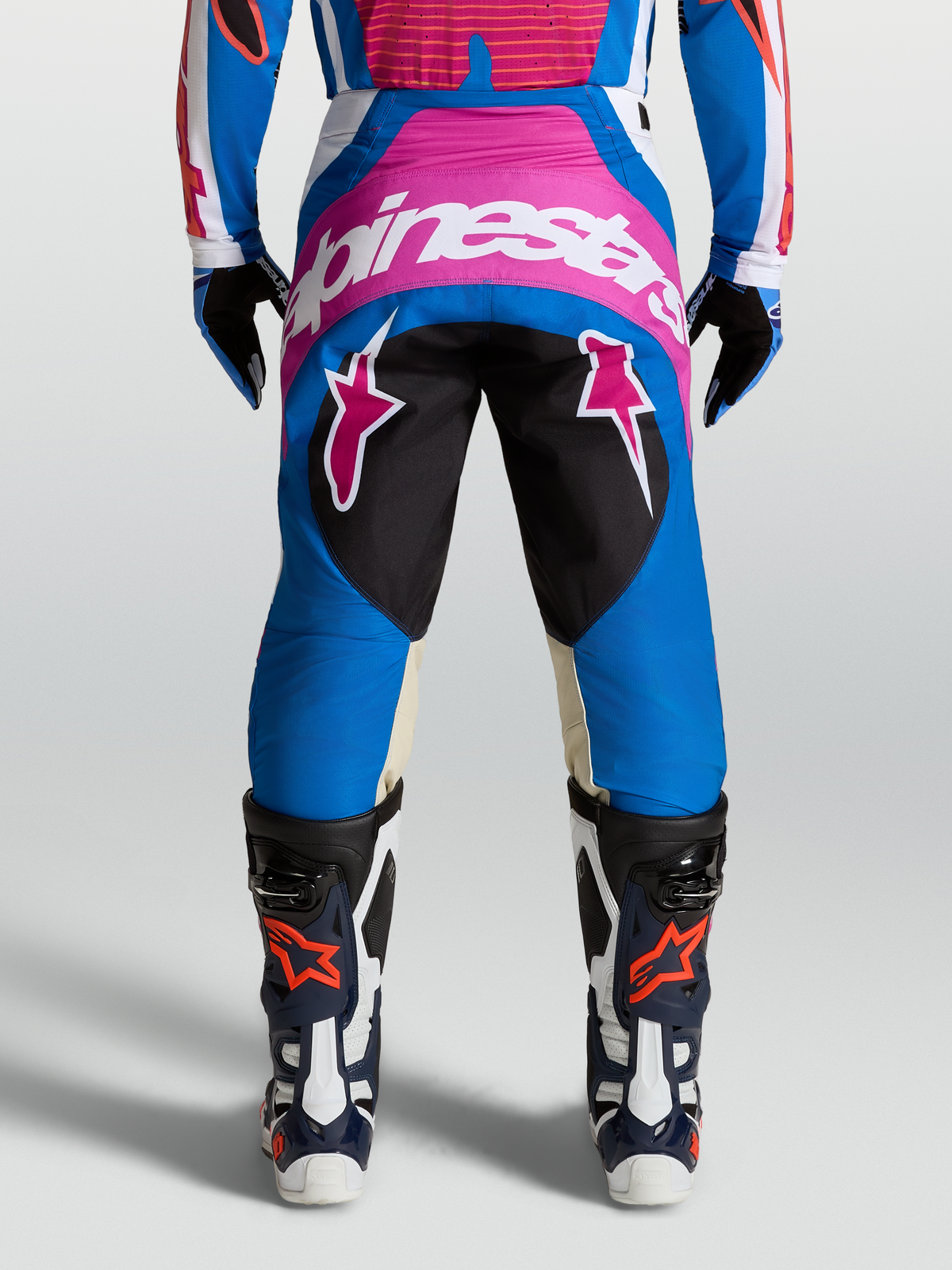 Alpinestars Techstar Maven Hose für Motocross, Blau und Pink mit weißem Schriftzug, Rückansicht am Model mit Stiefeln.