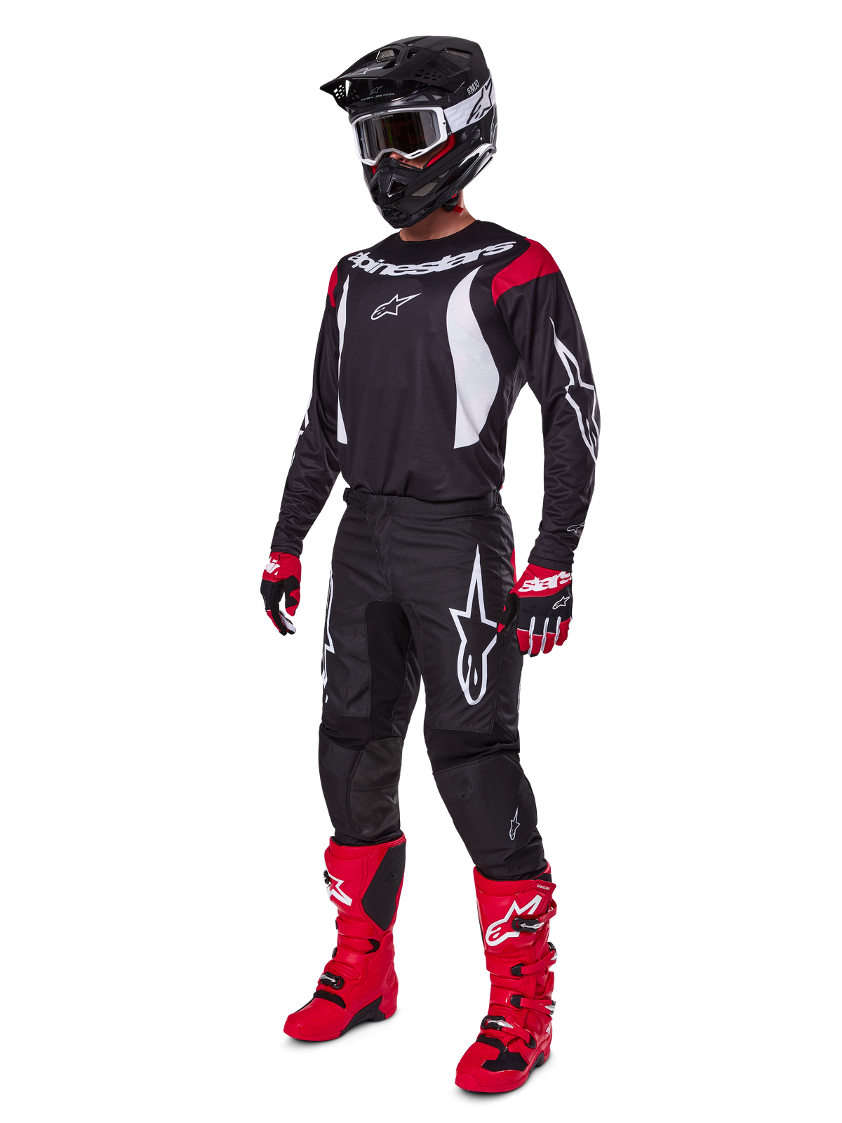 Motocross-Fahrer im kompletten Alpinestars 2025 Fluid Haul Ausrüstungsset, schwarzes Jersey mit roten und weißen Akzenten, schwarze Hose mit weißen Logos, leuchtend rote Stiefel, rote und schwarze Handschuhe, schwarzer Helm mit Brille, abgestimmte Offroad-Performance-Ausrüstung