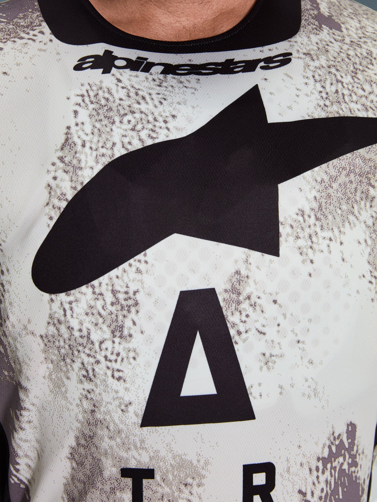 Alpinestars 2026 Racer Lahnd Trikot, Nahaufnahme des Brustbereichs, Sand Camo-Muster mit großem schwarzem Stern-Logo und Alpinestars-Schriftzug, atmungsaktives Performance-Polygewebe für Offroad-Fahrten