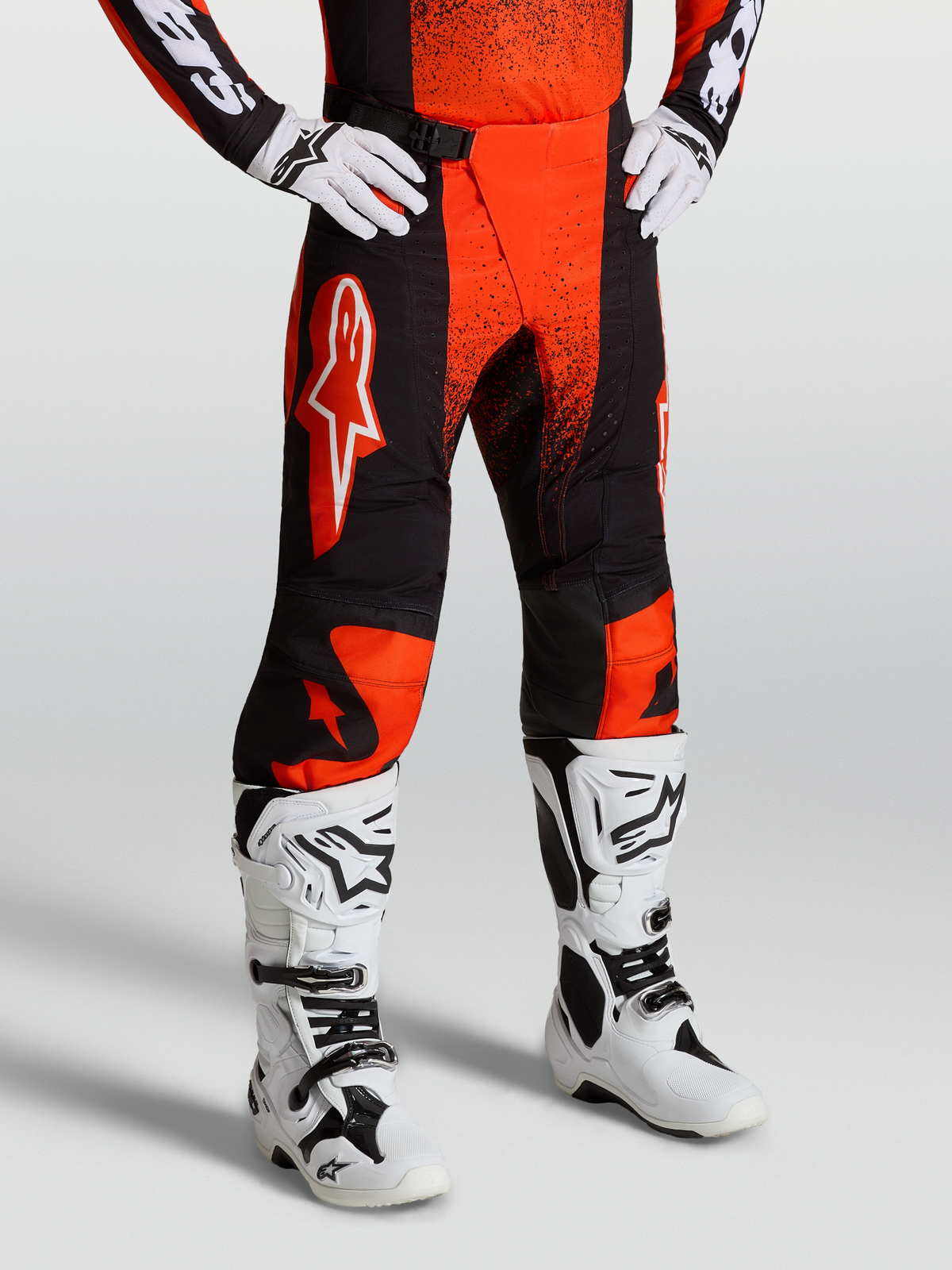Alpinestars Techstar Swan Hose, Motocross-Hose für Herren, Cardinal Rot und Schwarz, robustes Ripstop-Gewebe mit 4-Wege-Stretch-Einsätzen, getragen mit weißen Offroad-Stiefeln.