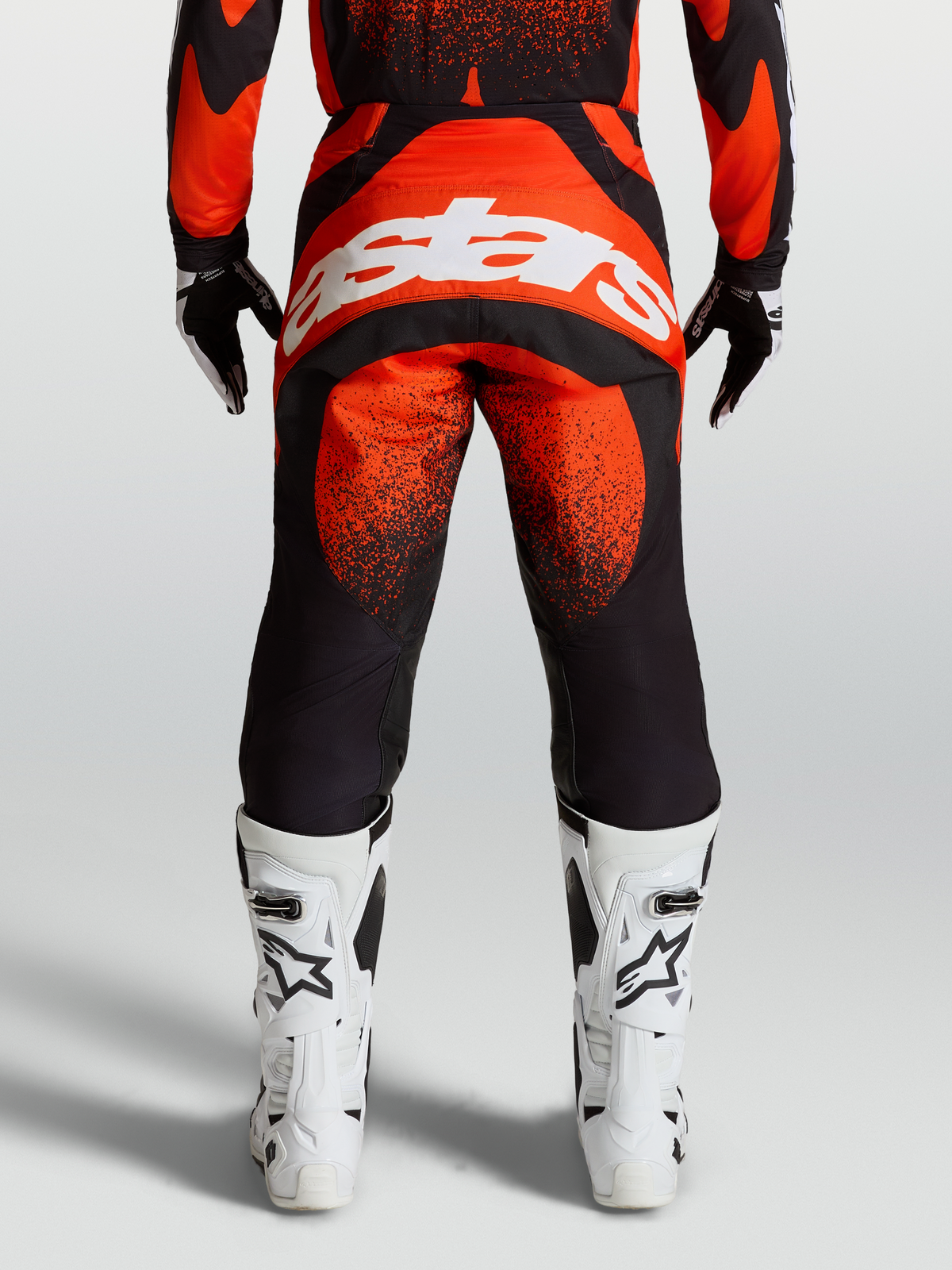 Alpinestars Techstar Swan Hose, MX-Hose in Rot und Schwarz, Rückansicht am Model mit weißem Astars-Logo und weißen Rennstiefeln, Offroad-Motocross-Ausrüstung