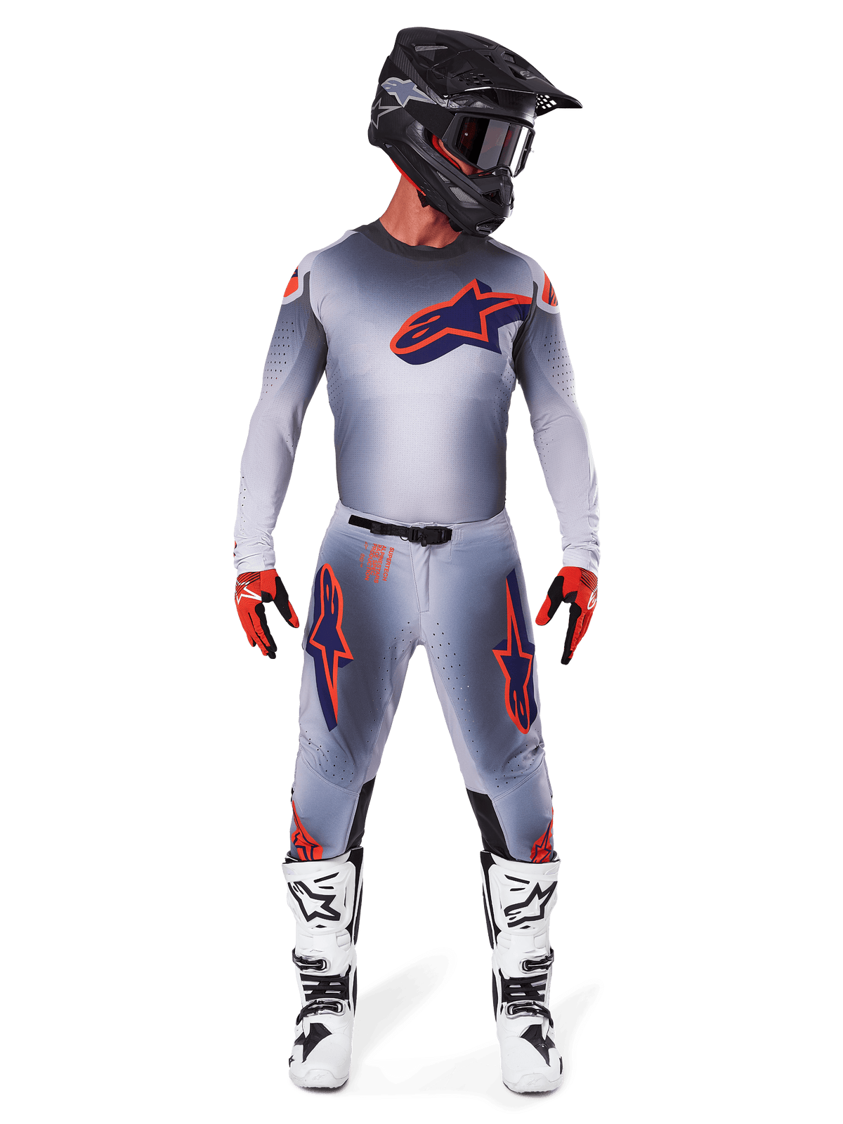 Motocross-Fahrer mit Alpinestars 2025 Supertech Lipan Hose und passendem Trikot in Gray Orange Fluo, markante orangefarbene und marineblaue Logos, kombiniert mit schwarzem Helm, roten Handschuhen und weiß-schwarzen Stiefeln, komplette Rennausrüstung für Offroad-Performance.