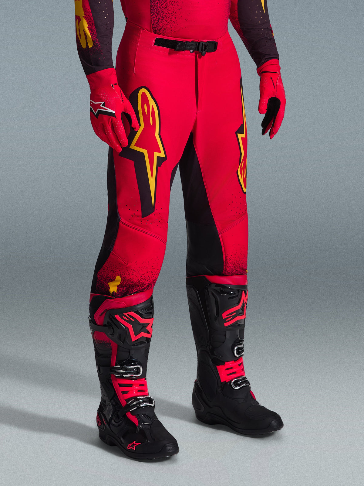 Alpinestars 2026 Supertech Scenz Hose, Motocross-Hose, Rot, Schwarz und Gelb, mit gelben Alpinestars-Logos und schwarzen Einsätzen, getragen mit passendem rotem Jersey, roten Handschuhen und schwarzen Motocross-Stiefeln.