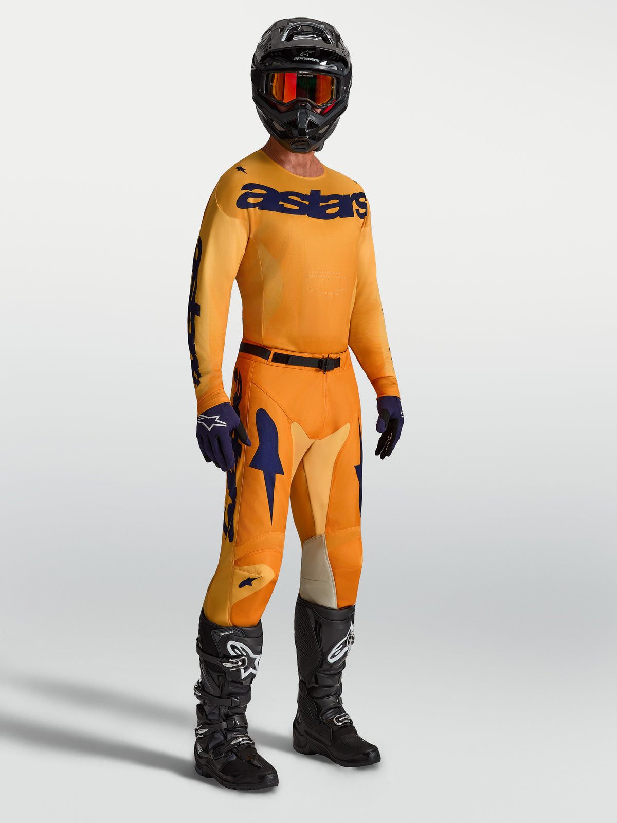 Alpinestars Racer Amber Pants and Jersey, Men's Motocross Racing Gear in Orange and Deep Blue with black boots and helmet.