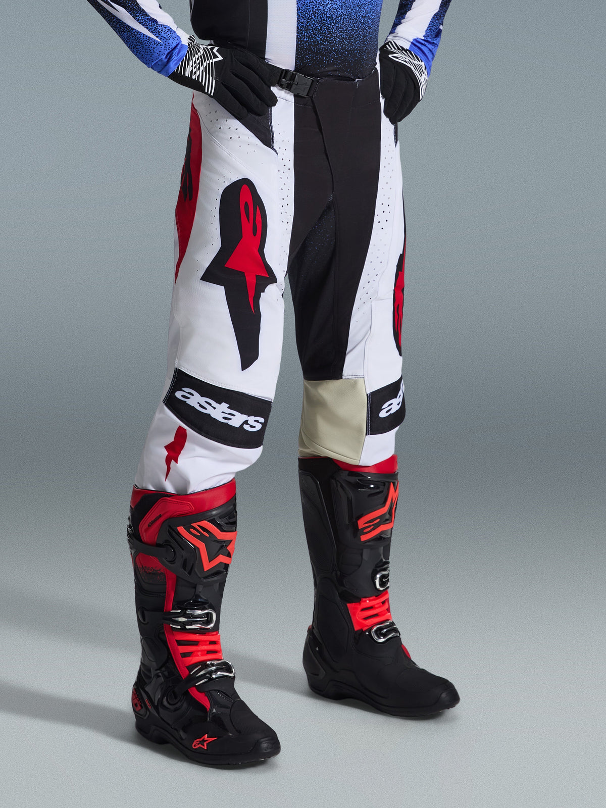 Alpinestars 2026 Techstar Knif Hose, Motocross-Hose, Schwarz, Weiß und Rot, getragen mit schwarz-roten Motocross-Stiefeln, auffälliges Astars-Branding an den Oberschenkeln, athletische Rennpassform, strapazierfähige Multi-Panel-Konstruktion für Offroad-Rennsport