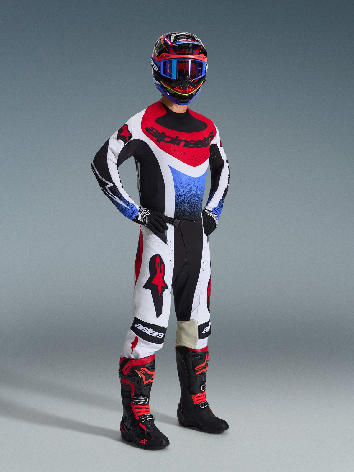 Alpinestars 2026 Techstar Knif Hose, Motocross-Hose, Schwarz, Weiß und Rot, getragen von einem Fahrer in kompletter Rennausrüstung mit passendem Jersey und Stiefeln, mit markanten roten Alpinestars-Logos auf weißen Einsätzen und einer leistungsorientierten sportlichen Passform.