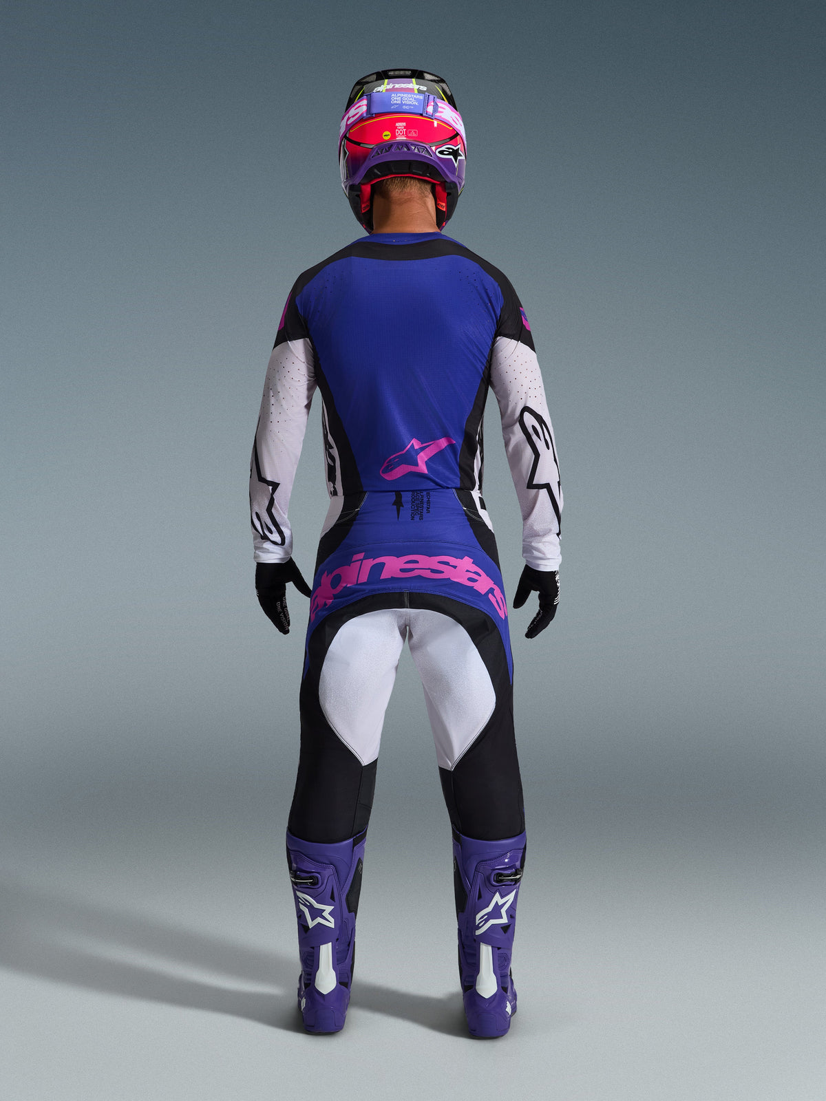 Alpinestars 2026 Techstar Knif Gear Set, Motocross rider rear view, Black Light Gray and Purple with pink logo, worn with matching purple boots and helmet, professional racing gear for off-road performance