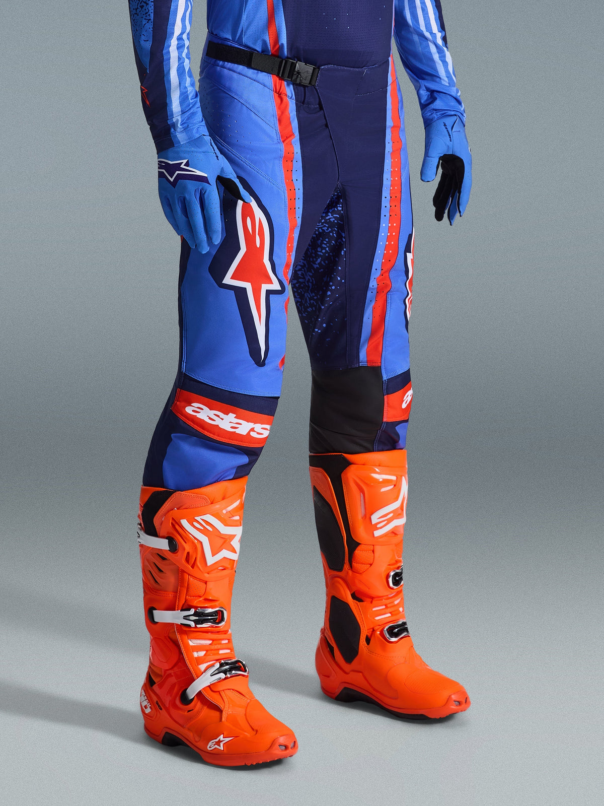 Alpinestars 2026 Techstar Nomur Hose, Motocross-Hose, Dunkelblau, Orange und UCLA-Blau, getragen mit leuchtend orangen Motocross-Stiefeln und passender blauer Ausrüstung, markantes Branding und Multi-Material-Konstruktion für Offroad-Performance.