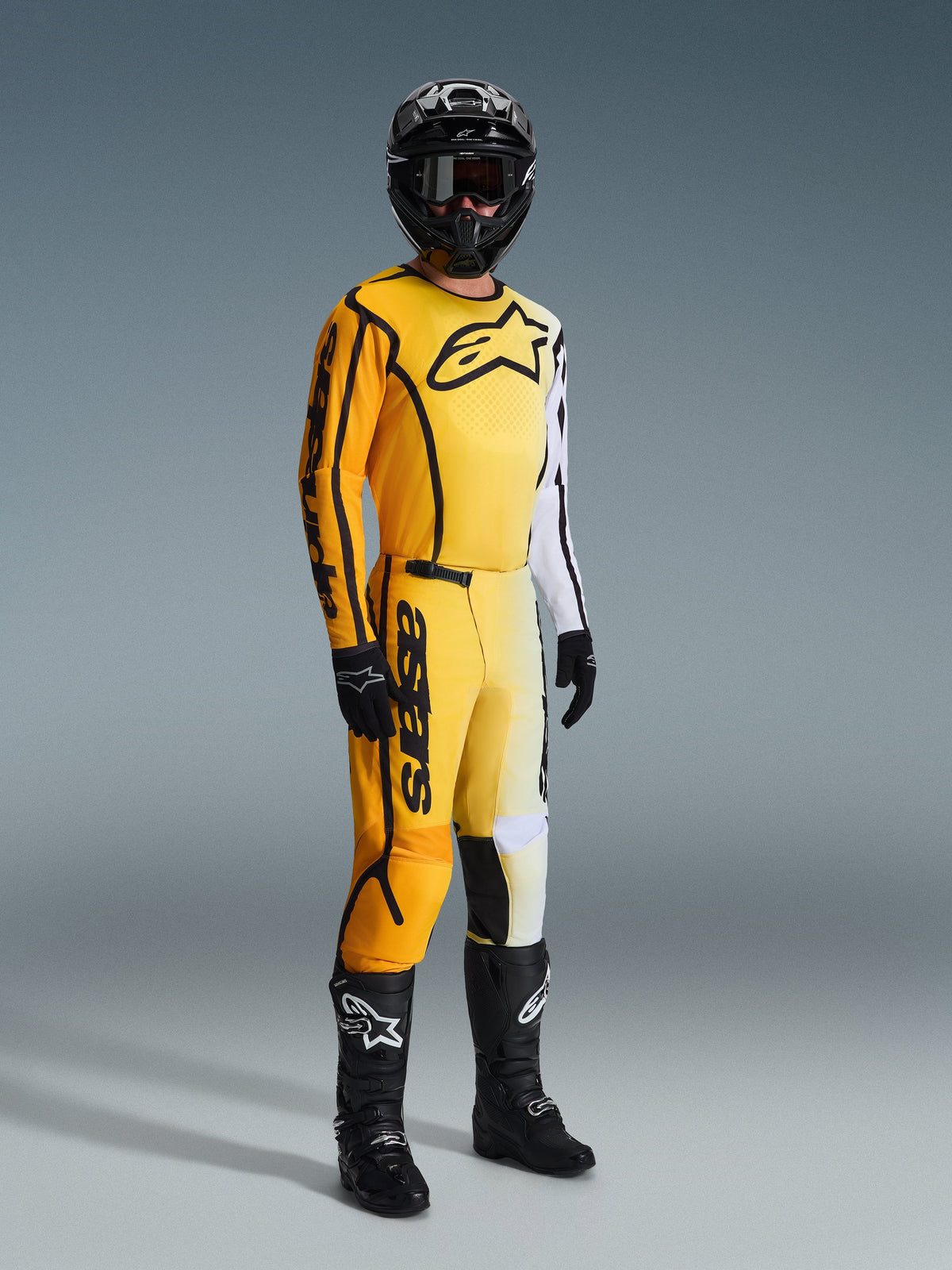 Alpinestars 2026 Fluid Apex Hose, Motocross-Hose, Gelb und Schwarz, getragen mit passendem gelb-weißem Trikot, schwarzem Helm, Goggles, Handschuhen und schwarzen Stiefeln, mit markantem schwarzem Branding und modernem Farbverlauf-Design für den Offroad-Rennsport.