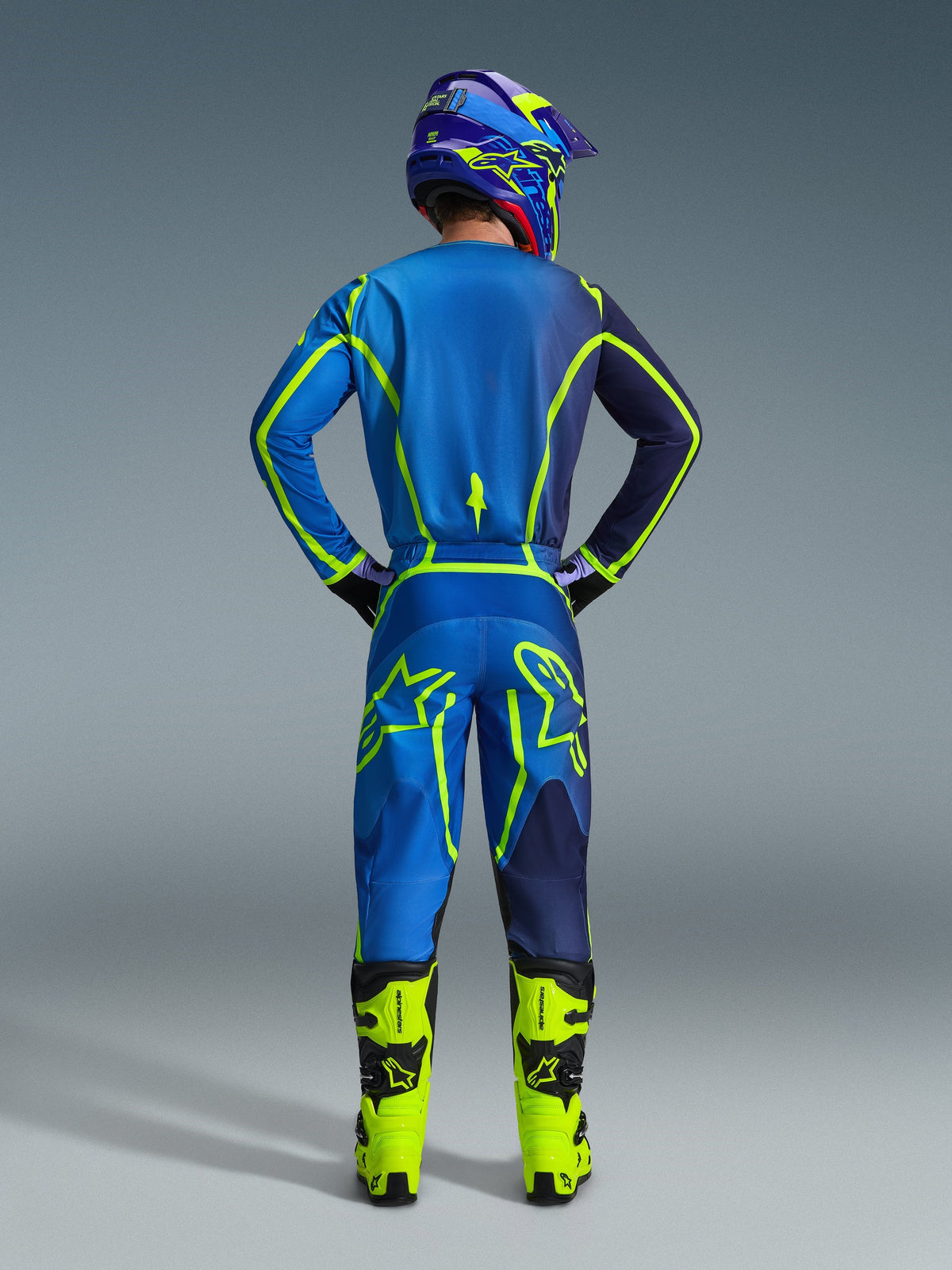 Alpinestars 2026 Fluid Apex Pants, Motocross Pants, Blue and Yellow Fluo, back view of rider in full racing gear, matching jersey and helmet, bright yellow boots, coordinated athletic fit for motocross.