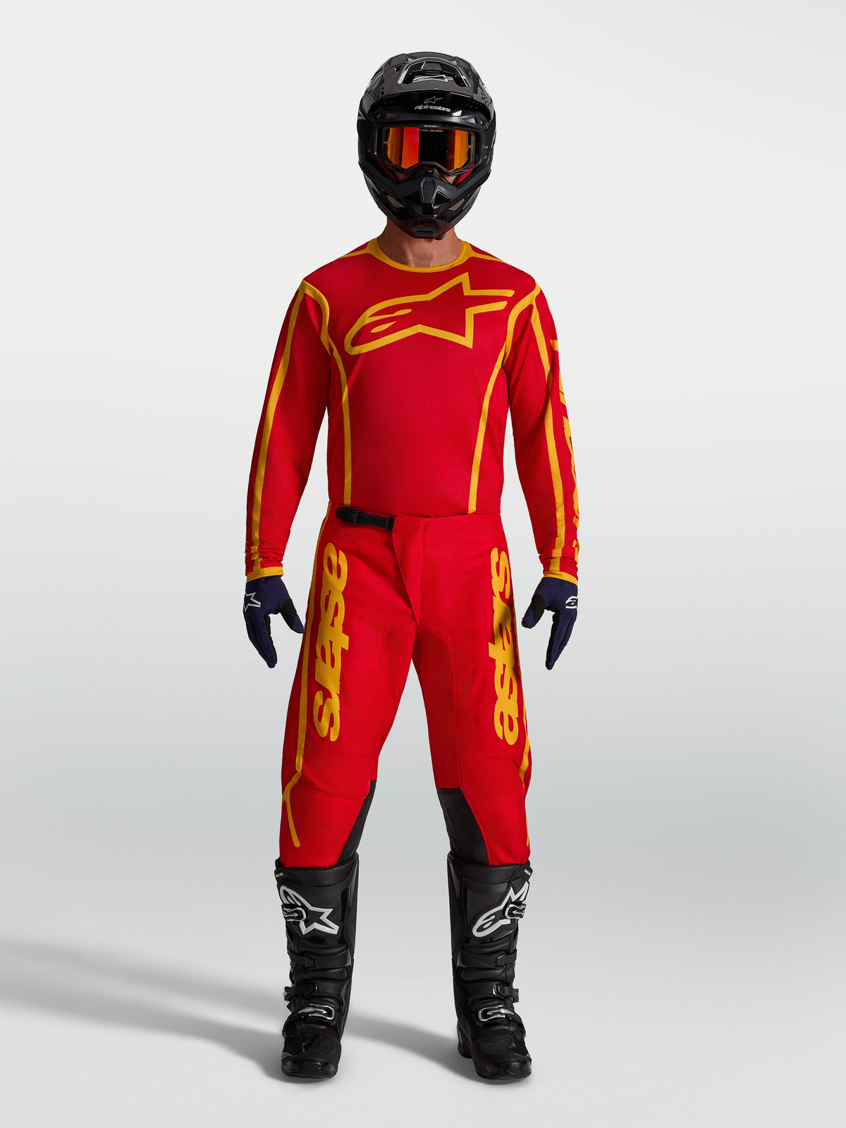 Alpinestars Fluid Apex V2 Hose, Herren-Motocross-Ausrüstung in Rot und Gold mit Trikot, schwarzem Helm und Stiefeln.
