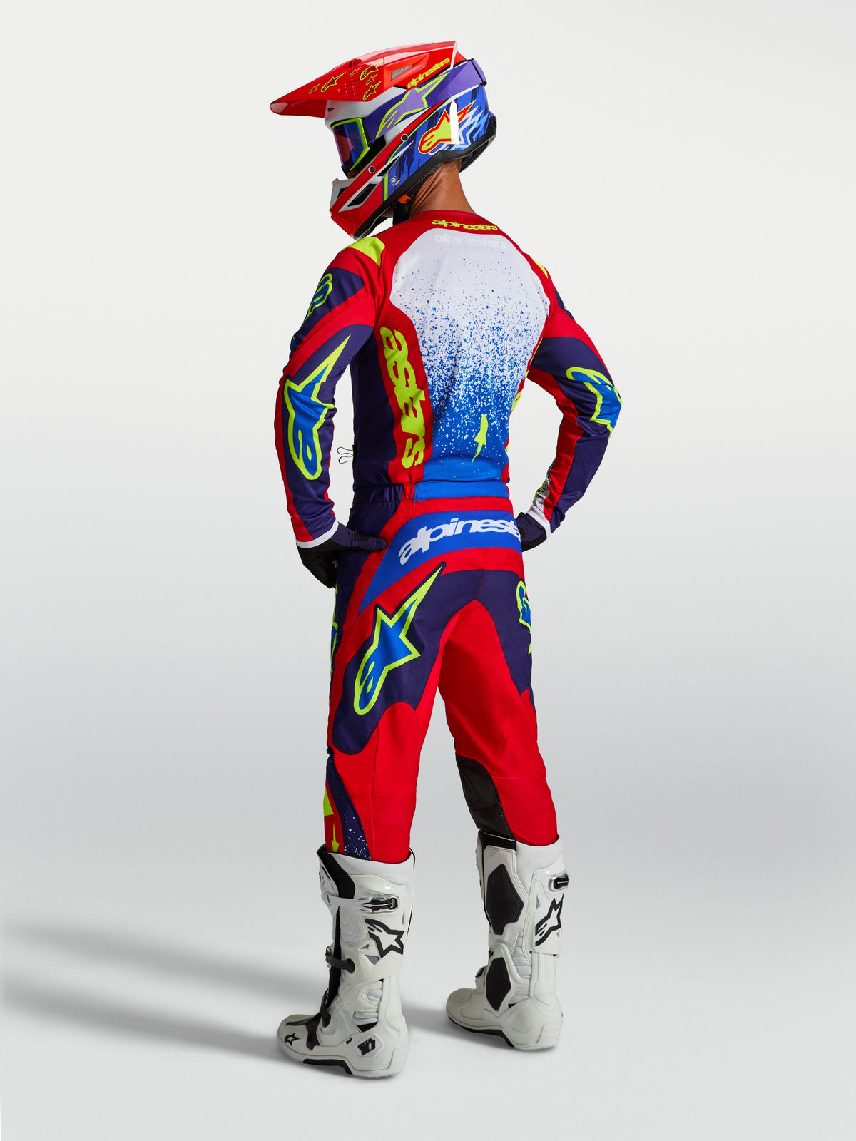 Alpinestars Fluid Drag Hose und 2027 Fluid Drag Gear Set, blau-rotes Herren-MX-Outfit mit weißen Stiefeln, Rückansicht.