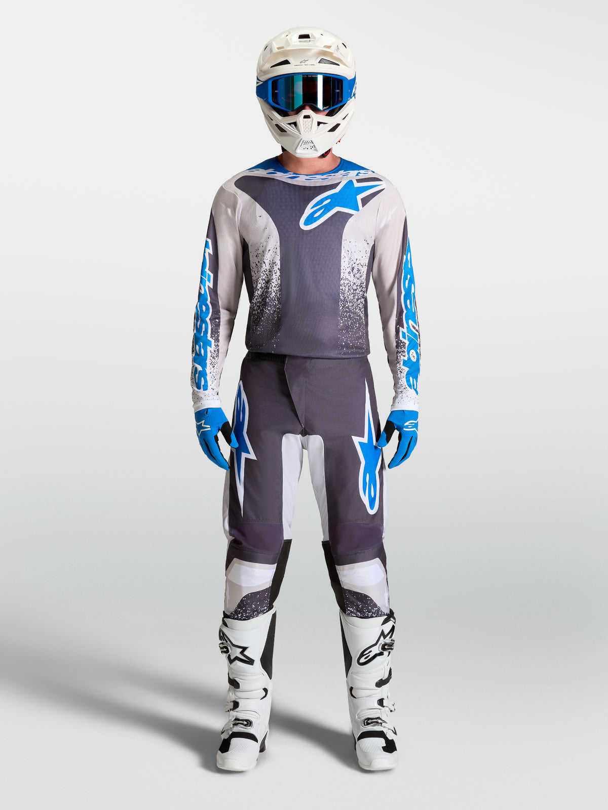 Alpinestars Fluid Drag Hosen, Motocross-Ausrüstung für Herren in Grau und Blau mit passendem Trikot und weißen Stiefeln.