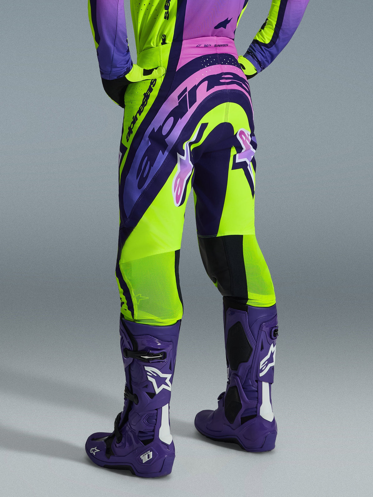 Alpinestars 2026 Supertech Vista Pants, Motocross Pants, Yellow Purple and Black, rear view worn with matching jersey and purple motocross boots, featuring bold branding and breathable mesh zones on the calves