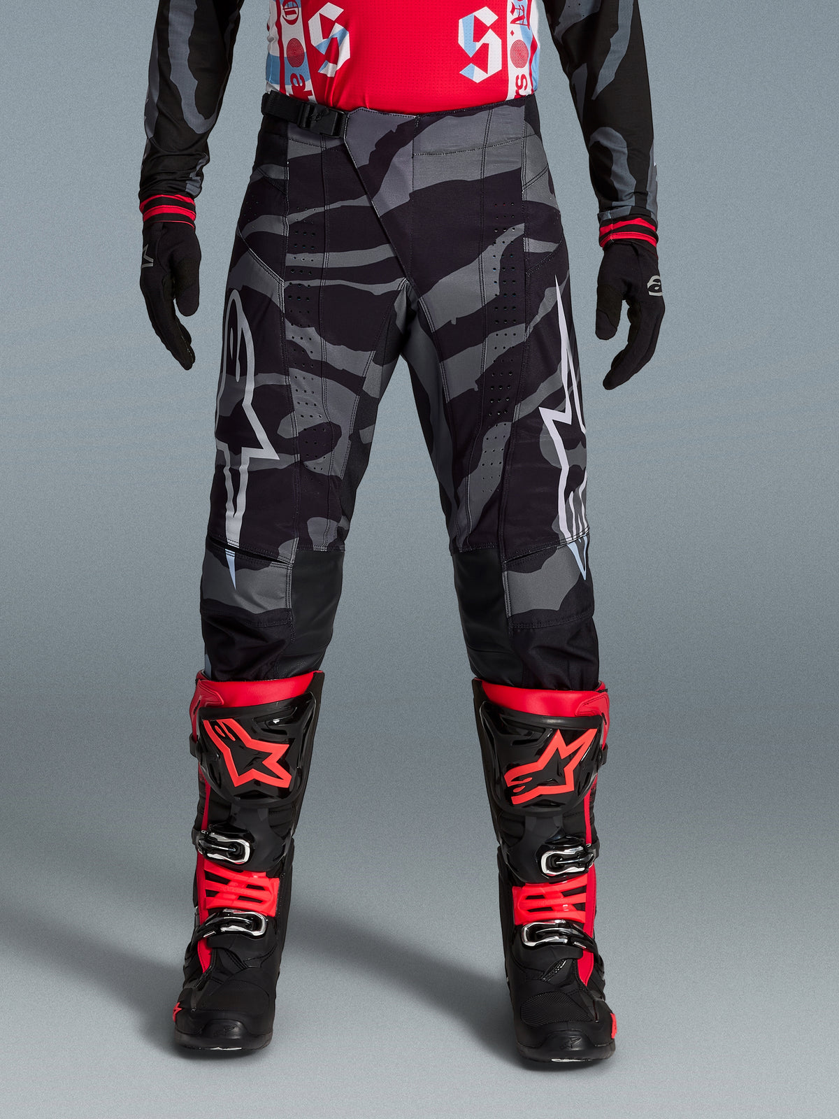 Alpinestars Limited Edition Techstar Beast Coast Hose, Motocross-Hose mit Camouflage-Muster in Schwarz und Grau, Teil einer Offroad-Ausrüstung mit orangefarbenen Akzenten.
