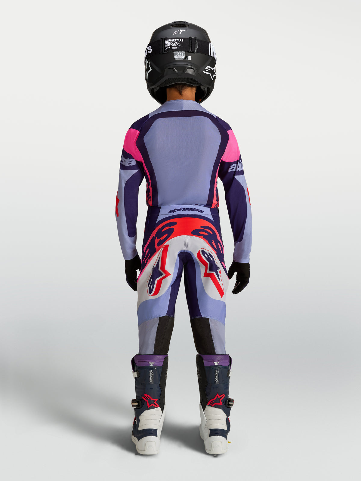 Alpinestars Jugend Supertech Dyna Hosen, Motocross-Rennhose für Kinder, Hellviolett und Lila, Rückansicht am jungen Fahrer mit Helm und Stiefeln, strapazierfähige MX-Bekleidung