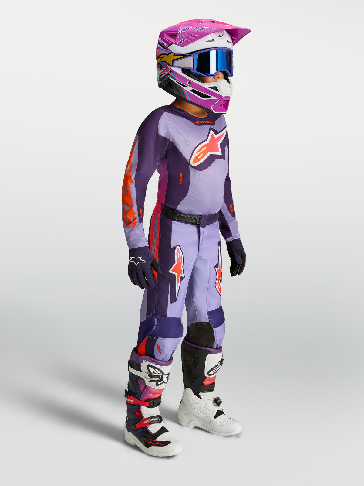 Alpinestars Fluid Hunt Jugend-Hose, Motocross-Set für junge Fahrer in Lila und Violett, mit Helm und Motorradstiefeln.