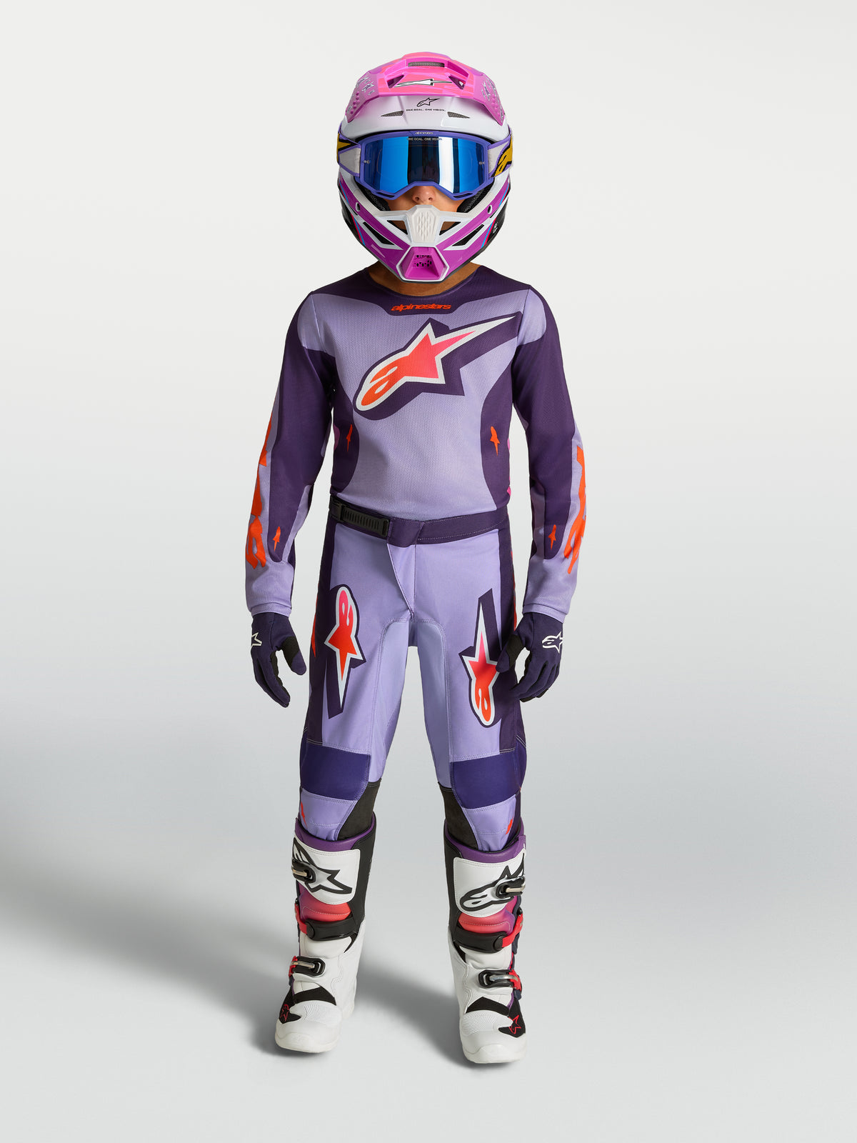 Alpinestars Fluid Hunt Jugend-Hose, lila und neonpinke MX-Hose für Motocross, strapazierfähiges 600D-Polygewebe, am Modell getragen als Teil einer kompletten Jugendschutzausrüstung.