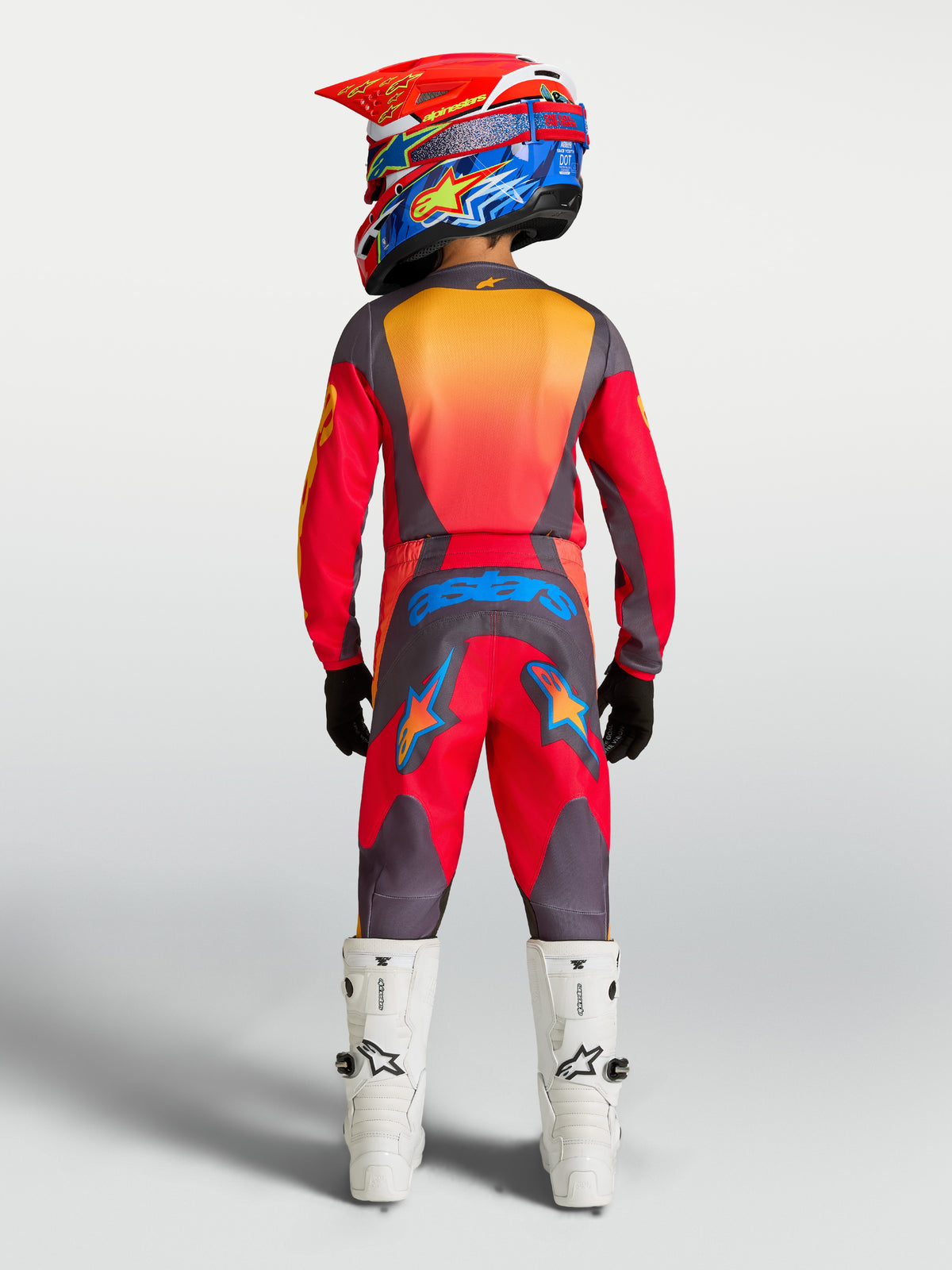 Alpinestars Jugend Fluid Hunt Hose, rote und graue Motocross-Hose, Rückansicht eines jungen Fahrers mit weißen Stiefeln.