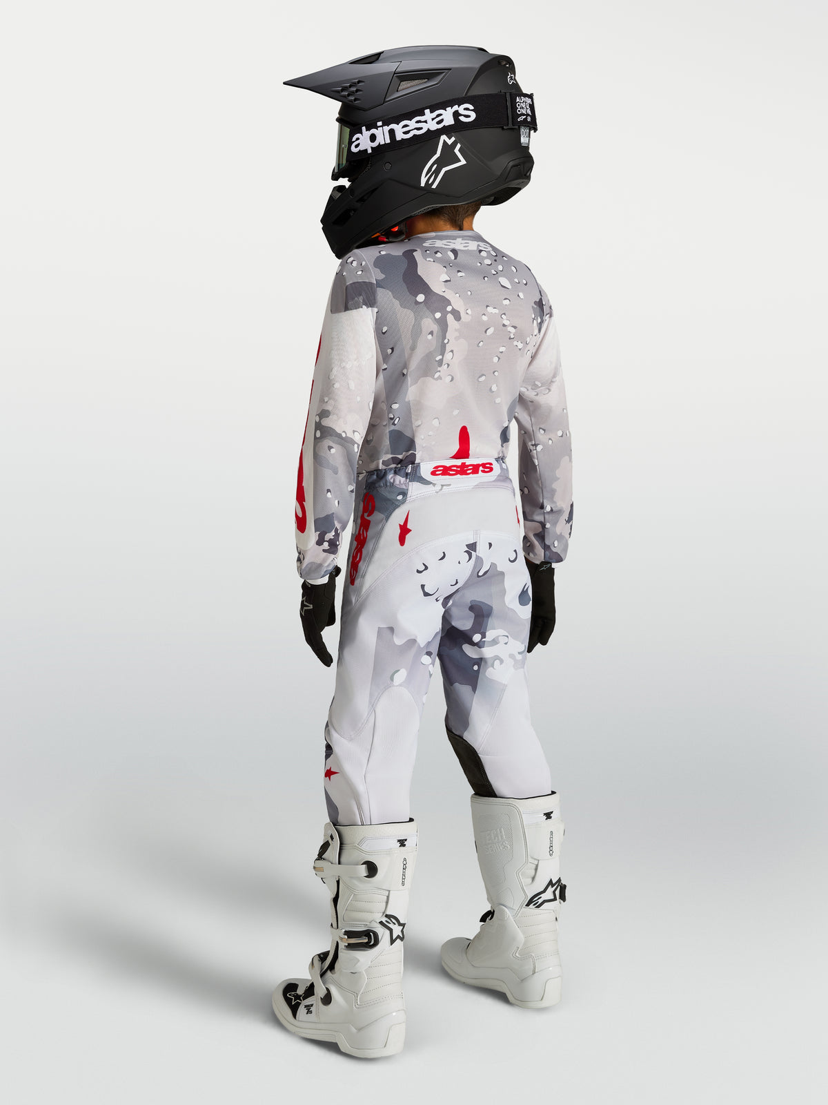 Alpinestars Fluid Jugend-Hose Lone 2027, Motocross-Hose für Kinder, Grau-Camo und Weiß mit roten Akzenten, Rückansicht an einem jungen Fahrer.