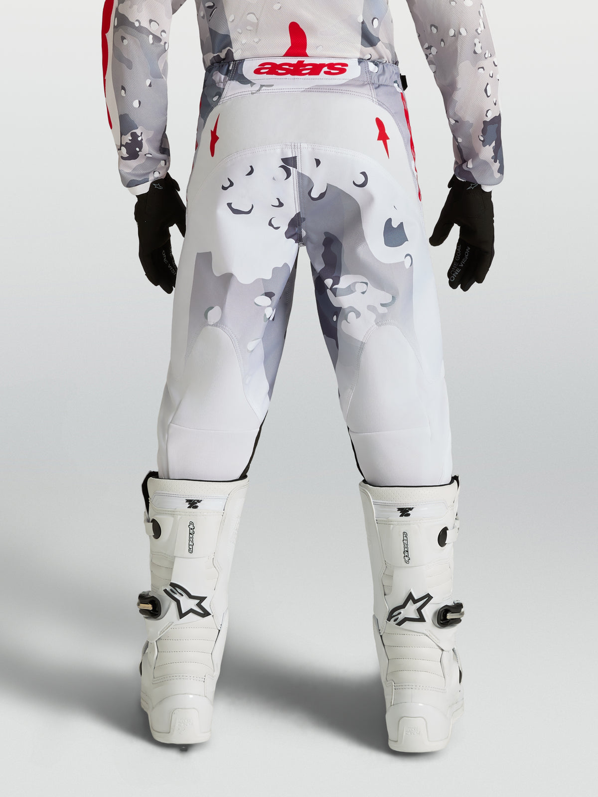 Alpinestars Fluid Jugend-Hose Lone 2027, Motocross-Hose in Grau-Camo und Weiß mit roten Akzenten, Rückansicht am Fahrer.