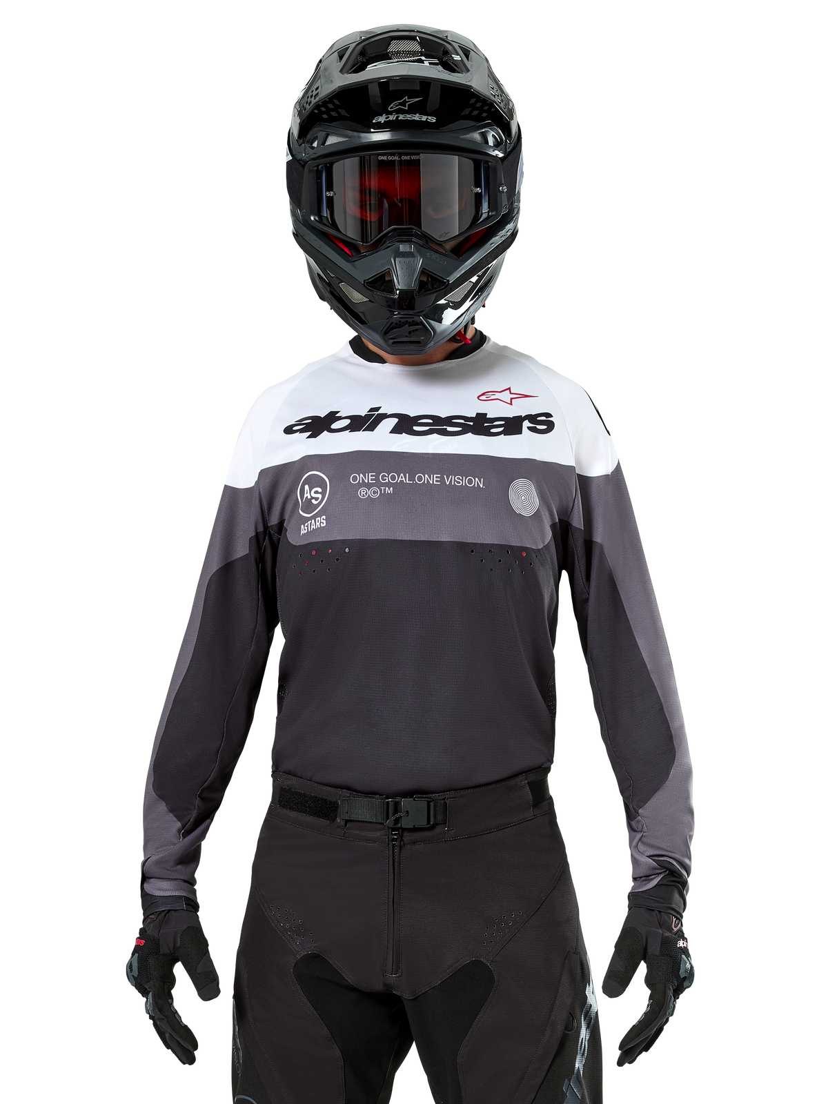 Motocross-Fahrer im Alpinestars Pro-Dura Jersey in Black Magnet White, langärmliges Performance-Oberteil mit weißen und grauen Farbblöcken, kombiniert mit schwarzem Helm und Schutzbrille, Alpinestars-Branding und „ONE GOAL ONE VISION“-Slogan, Offroad-Motorrad-Rennbekleidung