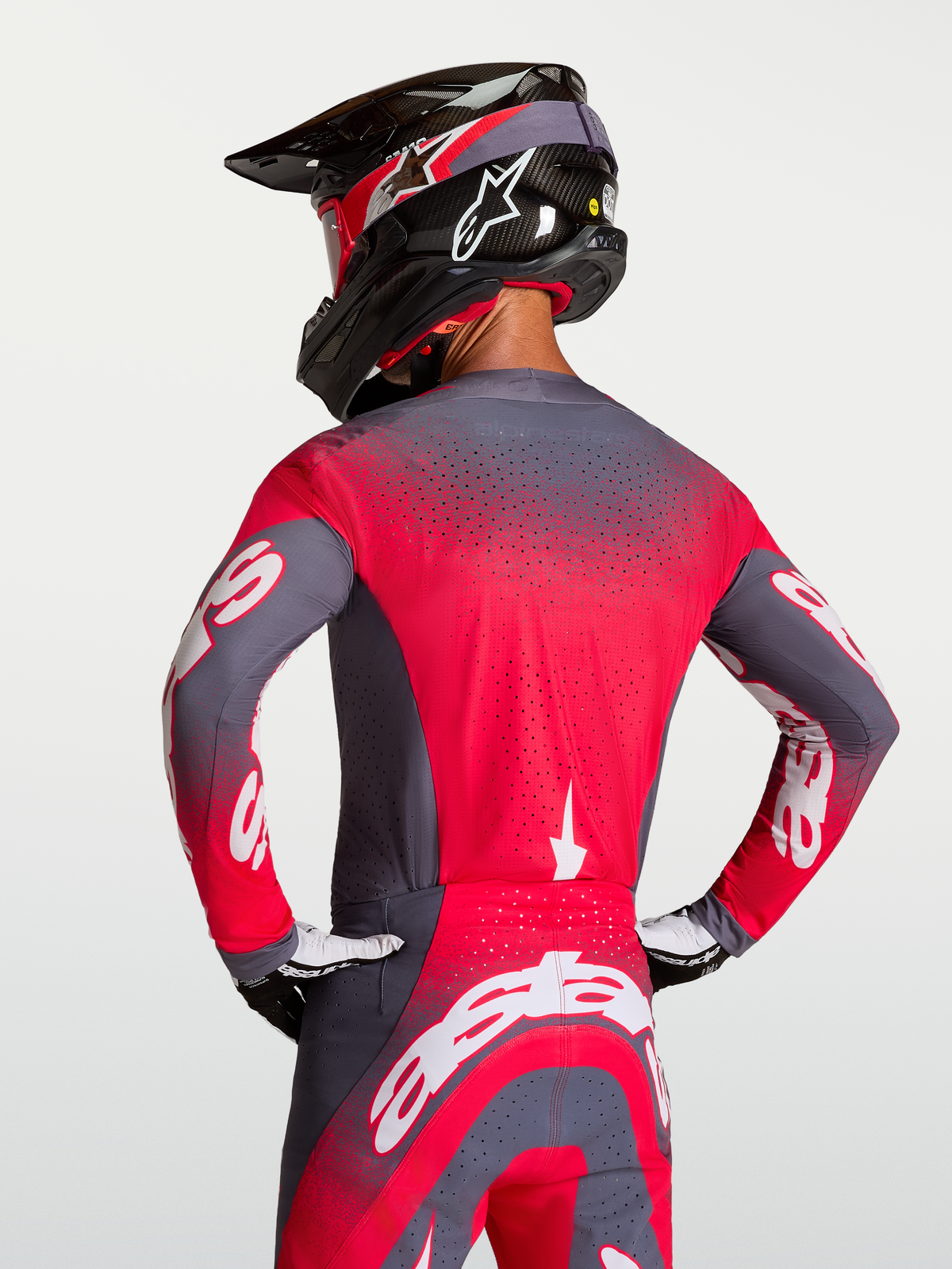 Alpinestars Supertech Hiten AFD Trikot, Motocross-Renntrikot in Grau und Rot, mit Belüftung am Rücken, getragen von einem Fahrer.