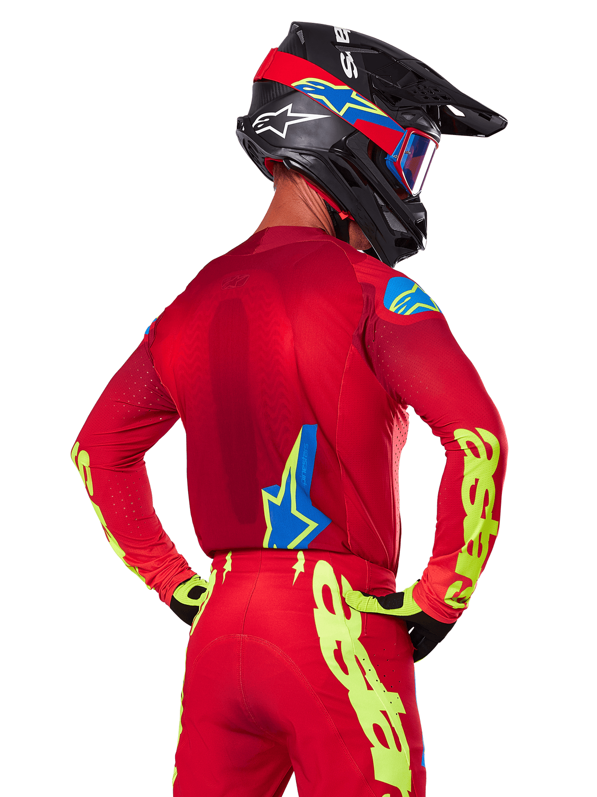 Rückansicht eines Motocross-Fahrers im Alpinestars 2025 Supertech Maker Gear Set in Rot, mit einem roten Trikot mit neongelbem Branding an den Ärmeln, einer passenden roten Hose, einem schwarzen Helm mit blauen und roten Akzenten sowie dazu passenden schwarz-gelben Handschuhen.