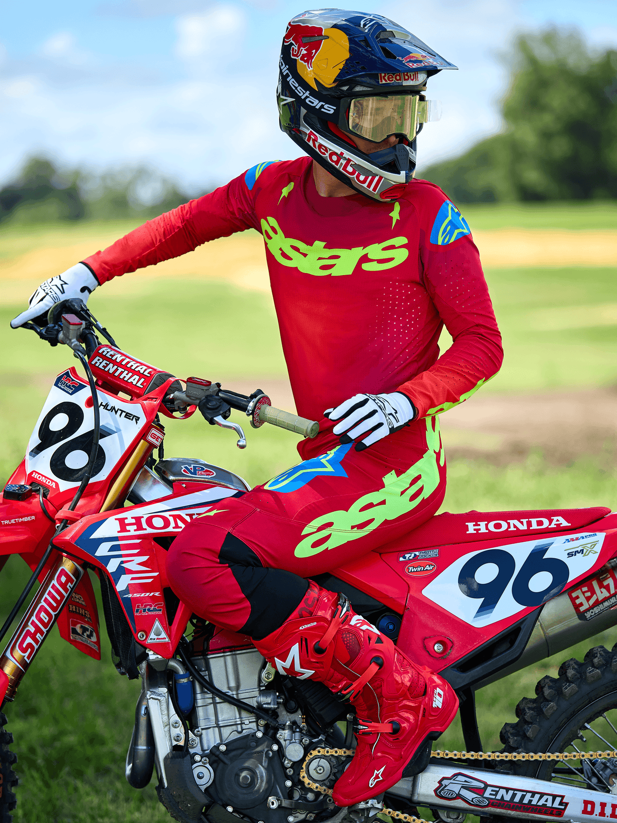 Motocross-Fahrer im Alpinestars 2025 Supertech Maker Trikot, leuchtendes Rot mit neongelbem 'astars'-Branding, kombiniert mit passender roter Hose und Stiefeln sowie weiß-schwarzen Handschuhen, sitzend auf einem roten Honda-Rennmotorrad im Freien.