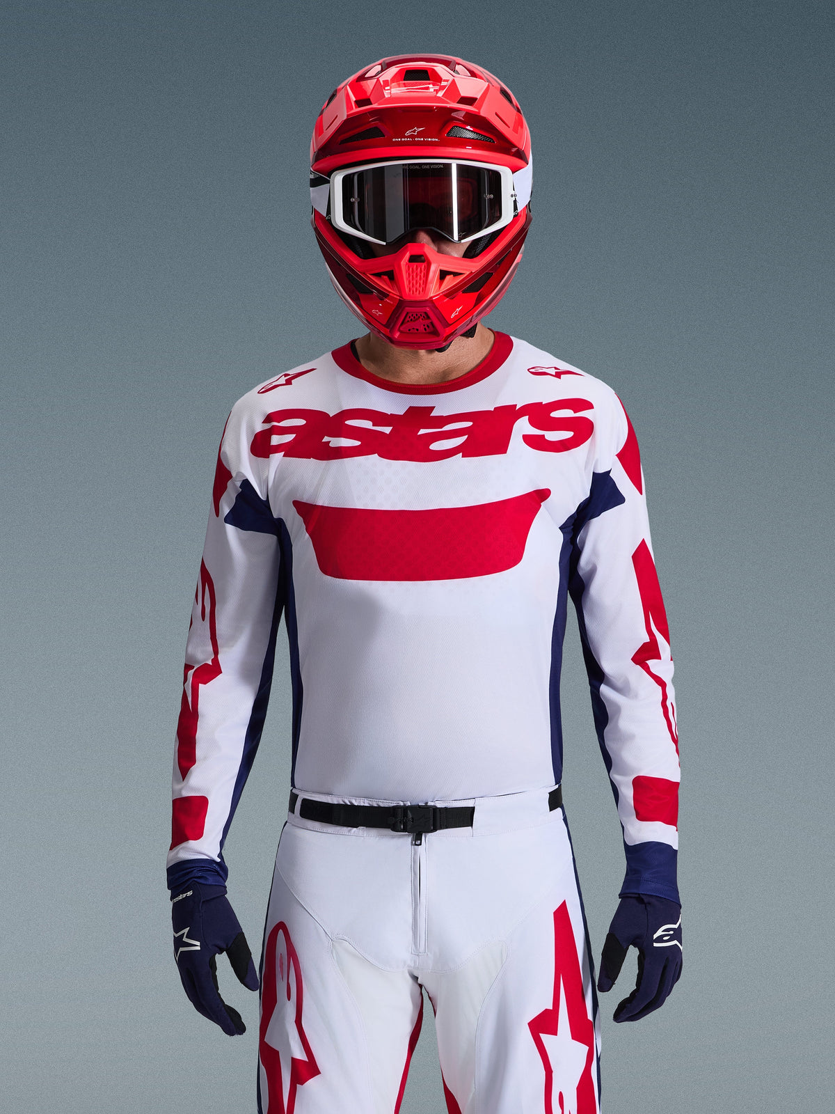Alpinestars 2026 Racer Riway Gear Set, Motocross-Fahrer in weißem Jersey mit rotem Branding und dunkelblauen Akzenten, passende weiße Hose mit roten Grafiken, roter Helm mit weißer Brille, dunkelblaue Handschuhe, professionell abgestimmtes Offroad-Rennoutfit