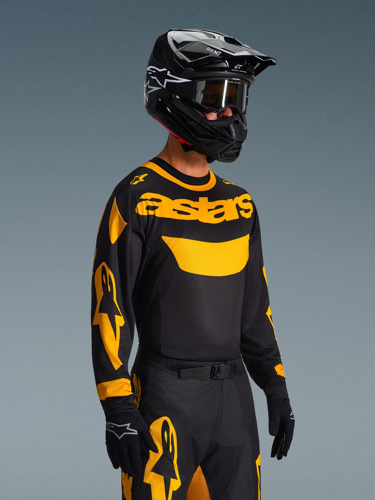 Motocross-Fahrer im Alpinestars 2026 Racer Riway Trikot in Gelb und Schwarz, schwarzes Trikot mit markantem gelbem „astars“-Branding und Ärmelgrafiken, passende schwarz-gelbe Hose, schwarzer Helm mit Goggles und schwarze Handschuhe, professionelle Offroad-Rennausrüstung
