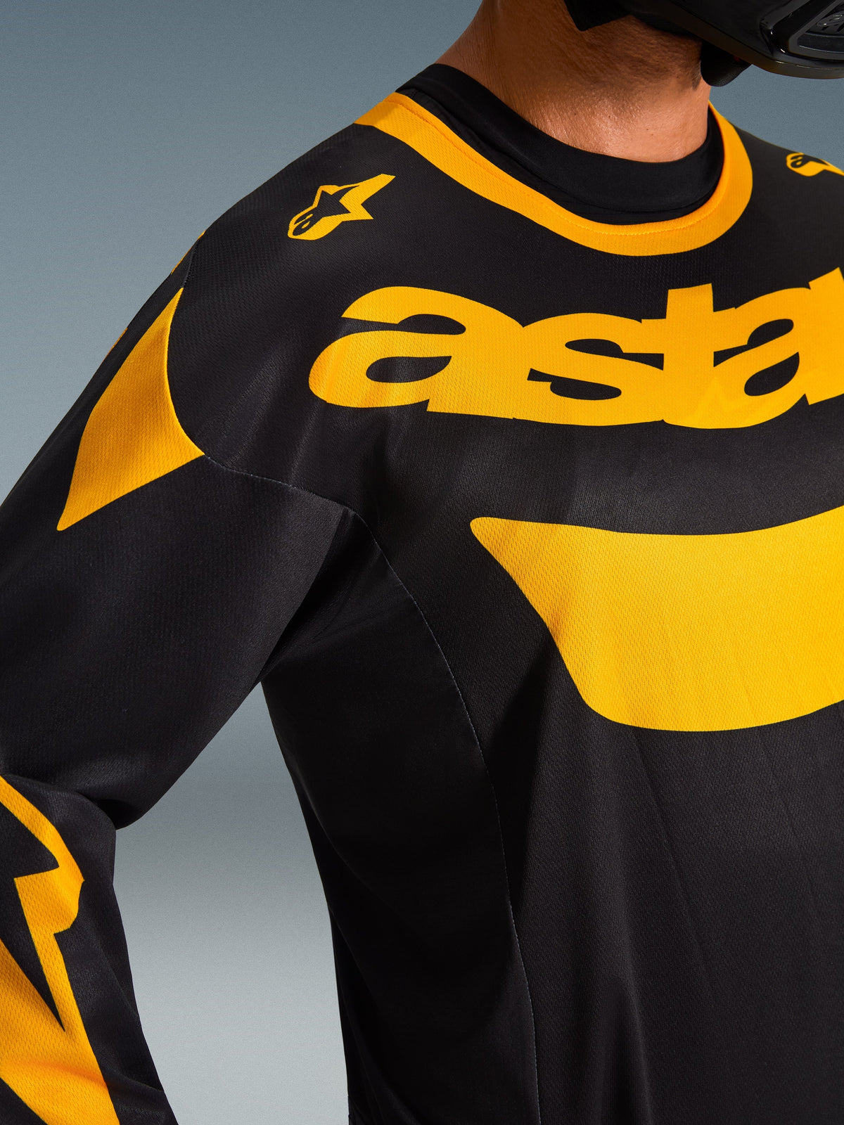 Alpinestars 2026 Racer Riway Trikot, Motocross-Trikot, Gelb und Schwarz, Nahaufnahme des Brust- und Schulterbereichs mit markantem gelbem „astars“-Branding und grafischen Akzenten auf schwarzem Polygewebe, Performance-Offroad-Ausrüstung.