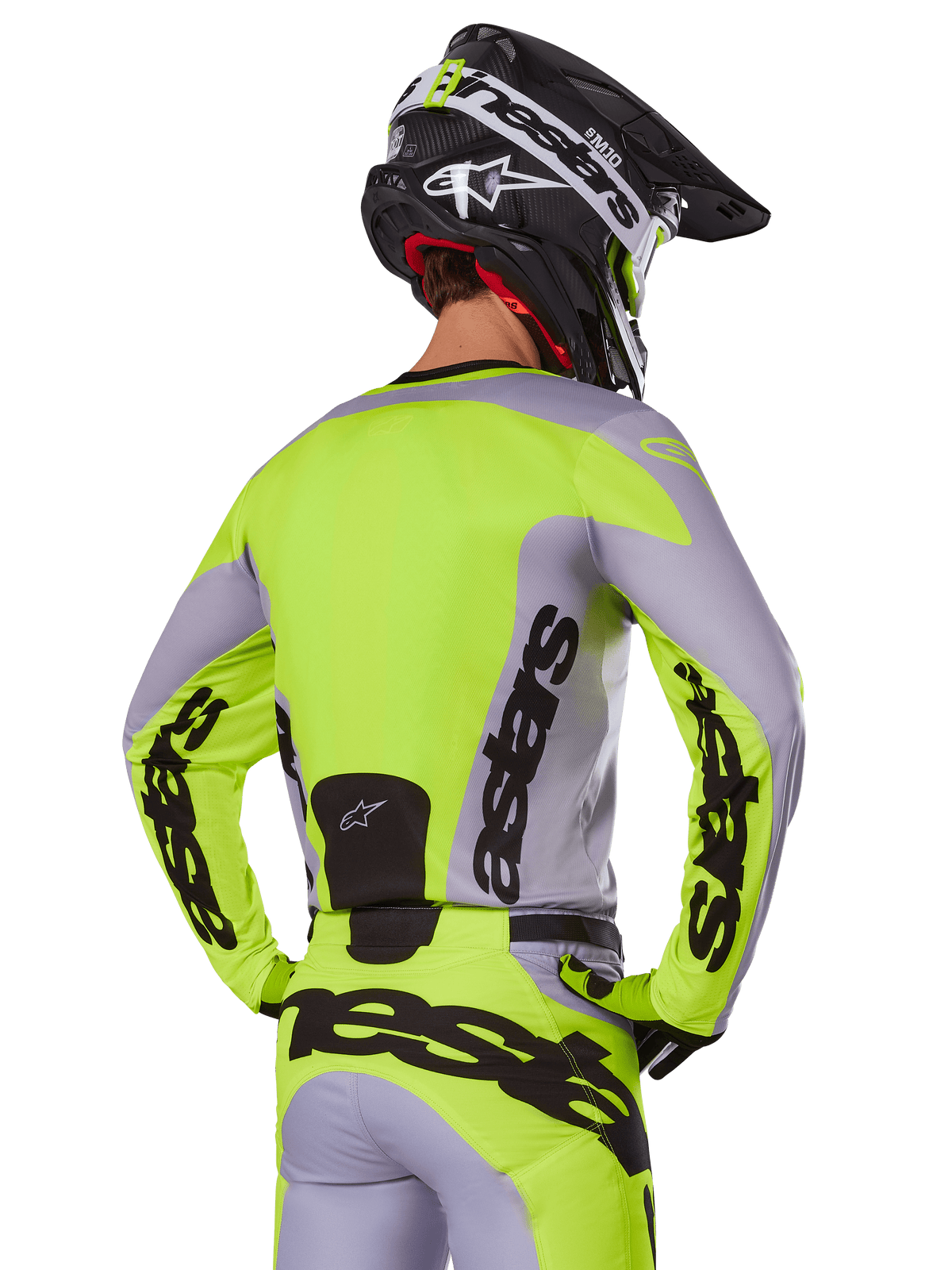 Motocross-Fahrer von hinten im Alpinestars 2025 Racer Veil Trikot in Grau und Gelb Fluo, mit markantem „astars“-Branding auf dem Rücken und den Ärmeln, kombiniert mit der passenden Hose und einem schwarzen Helm für einen kompletten Racing-Look.