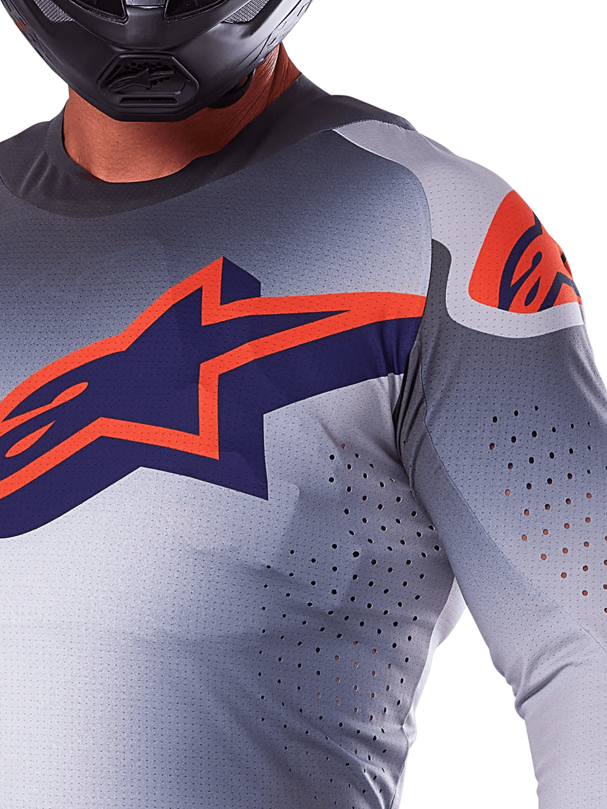 Nahaufnahme eines Fahrers im Alpinestars 2025 Supertech Lipan Trikot, Motocross-Trikot, Grau und Orange Fluo, mit einem großen orangen Alpinestars-Logo auf der Brust, lasergeschnittenen Belüftungsöffnungen und einem schwarzen Helm, professionelle Rennausrüstung.