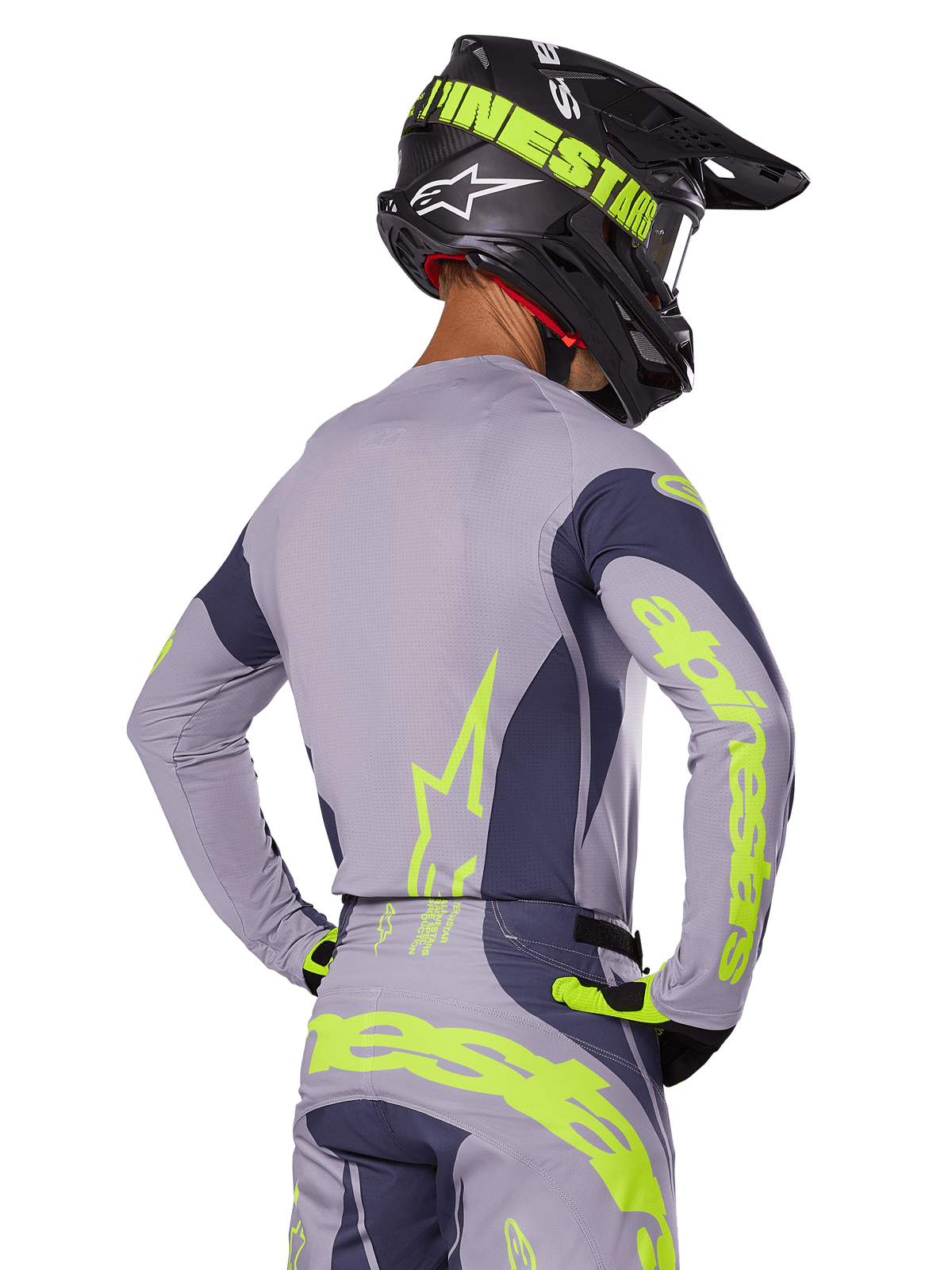 Motocross-Fahrer in der Rückansicht im Alpinestars 2025 Techstar Dreem Gear Set, graues Jersey und Hose mit leuchtend neongelbem Branding, passender schwarzer Helm mit Neon-Grafiken, professionelle Motocross-Rennausrüstung