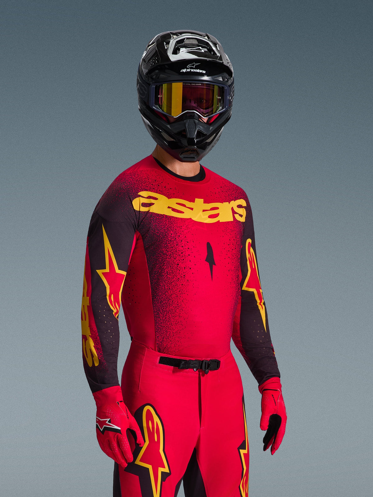 Motocross-Fahrer im Alpinestars 2026 Supertech Scenz Trikot in Rot und Schwarz mit gelbem 'astars' Branding, passende rote Hose und Handschuhe, schwarzer Helm mit Brille, professionelles Rennsport-Ausrüstungsset für Offroad-Motocross