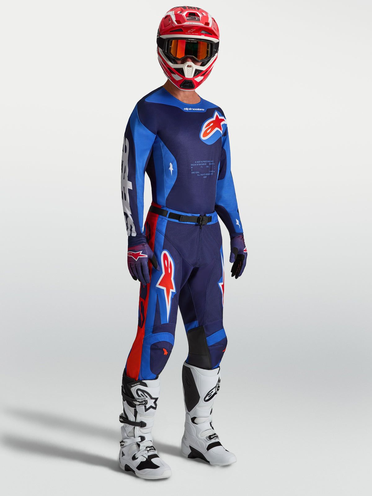 Alpinestars 2027 Racer Hunt Gear Set, navy and blue motocross outfit with red accents, white boots, and red racing helmet.