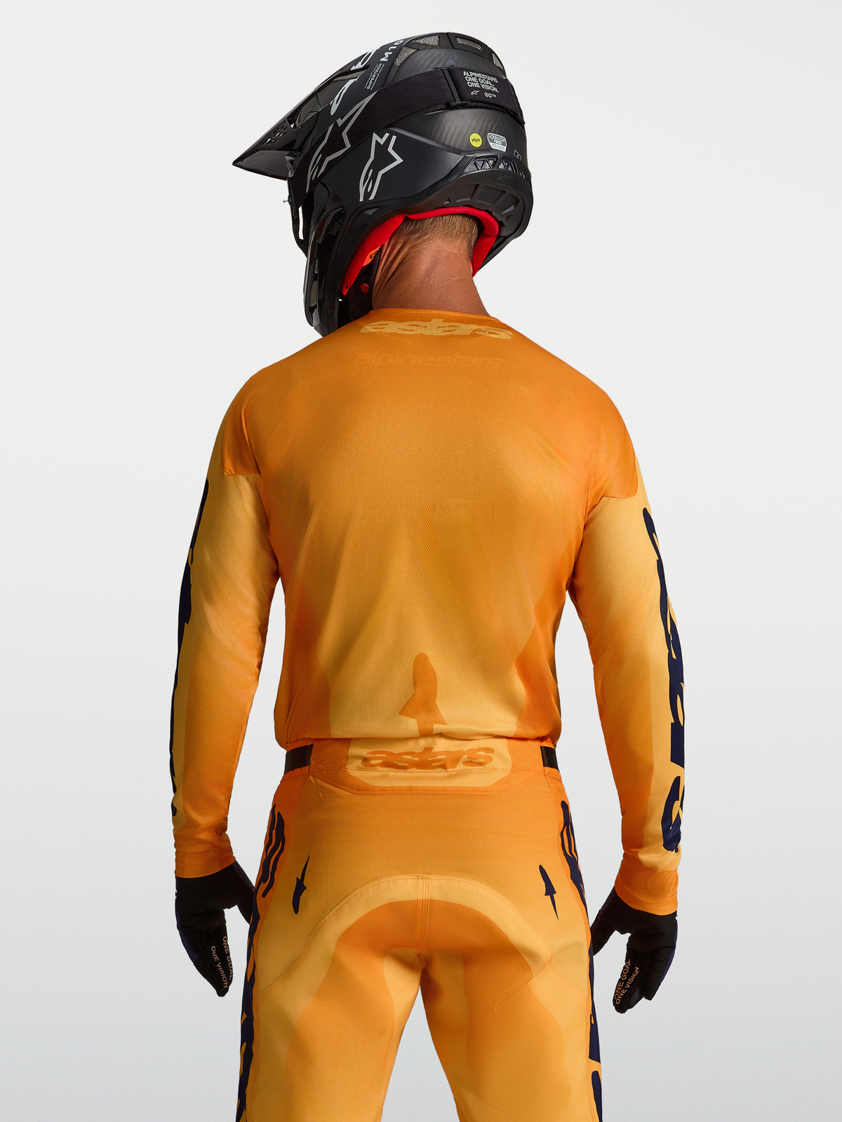 Alpinestars Racer Amber Jersey, men's orange and gold motocross top with breathable mesh panels, shown from the back on model.