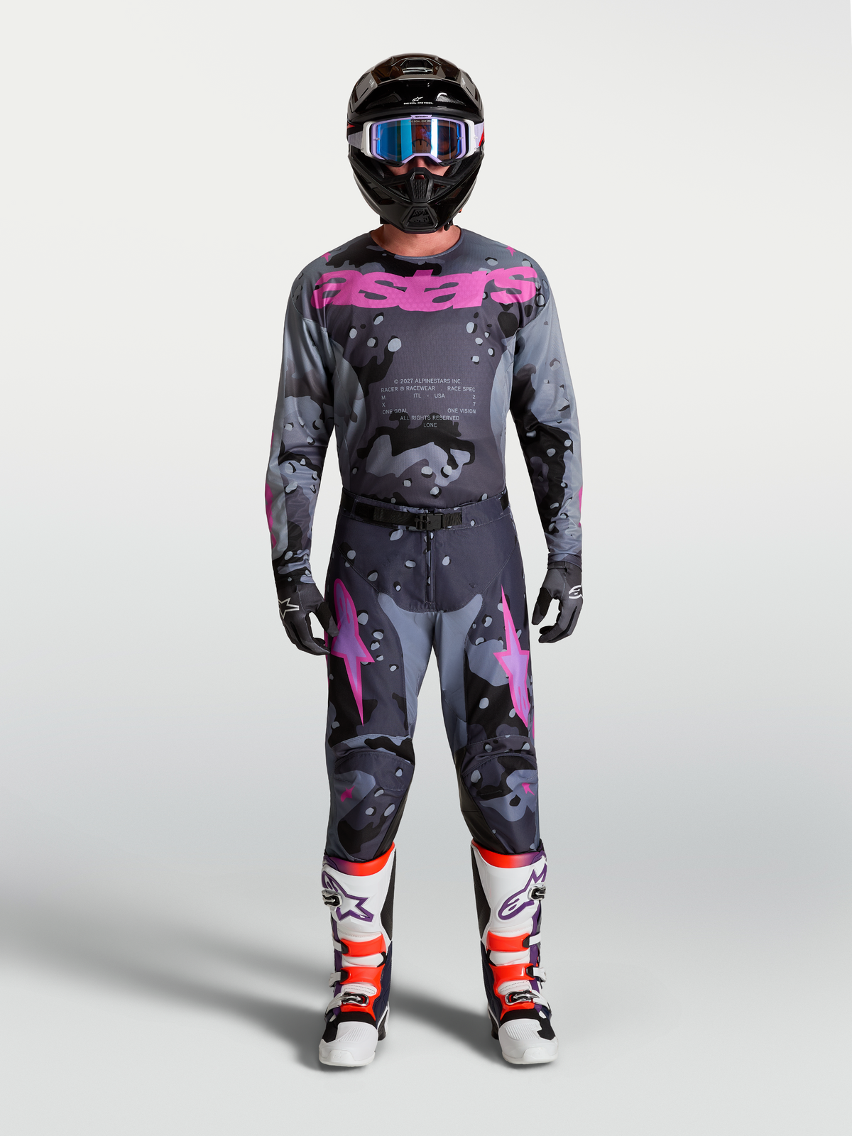 Alpinestars Racer Lone Jersey, men's gray camo and purple motocross gear set with helmet and protective boots.