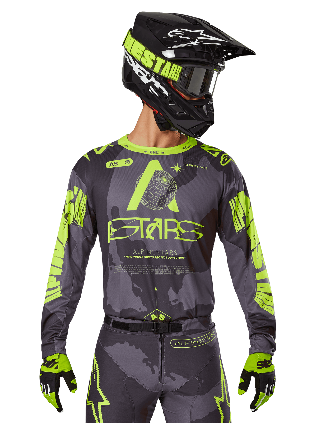 Alpinestars 2025 Racer Hollow Trikot, Motocross-Renntrikot, Dunkles Camo und Neongelb, getragen mit passender Hose, schwarz-gelbem Helm mit Brille und schwarzen Handschuhen, mit Alpinestars-Branding und Camouflage-Design