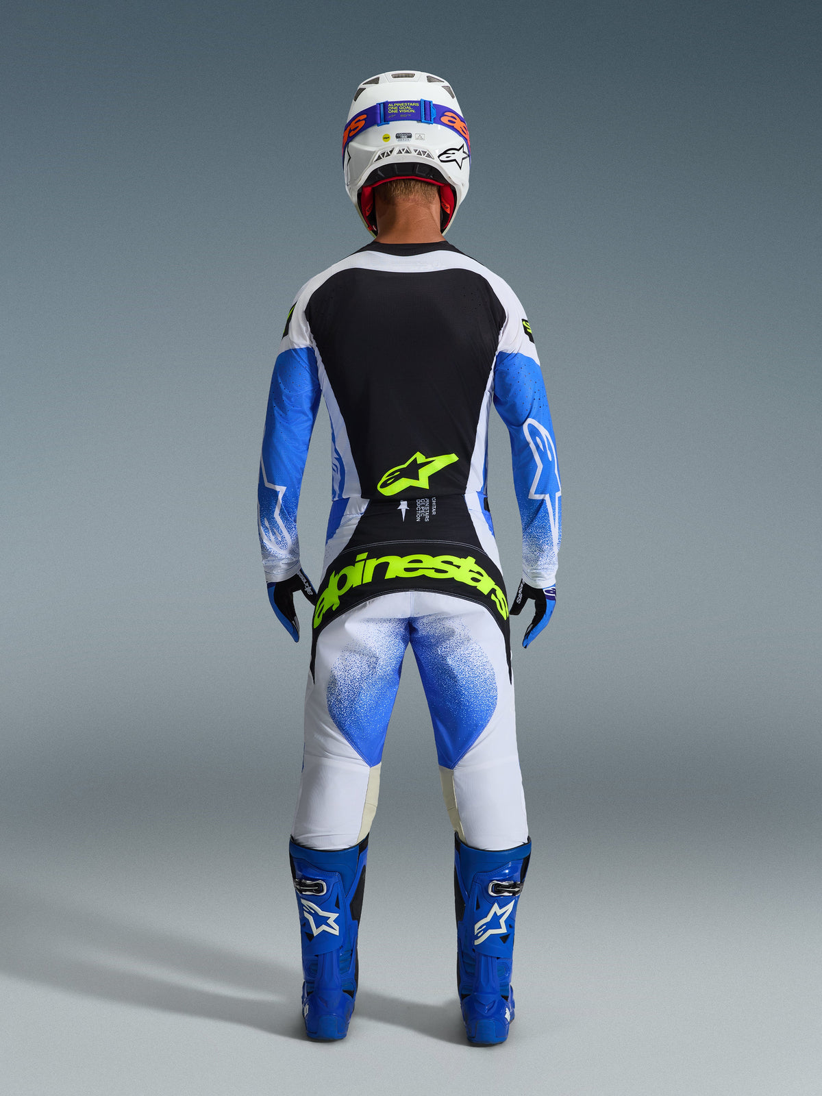 Alpinestars 2026 Techstar Knif Gear Set, back view of a motocross rider in Ucla Blue, Black, and White, featuring Yellow Fluo branding on the jersey and pants, paired with blue racing boots and a white helmet.