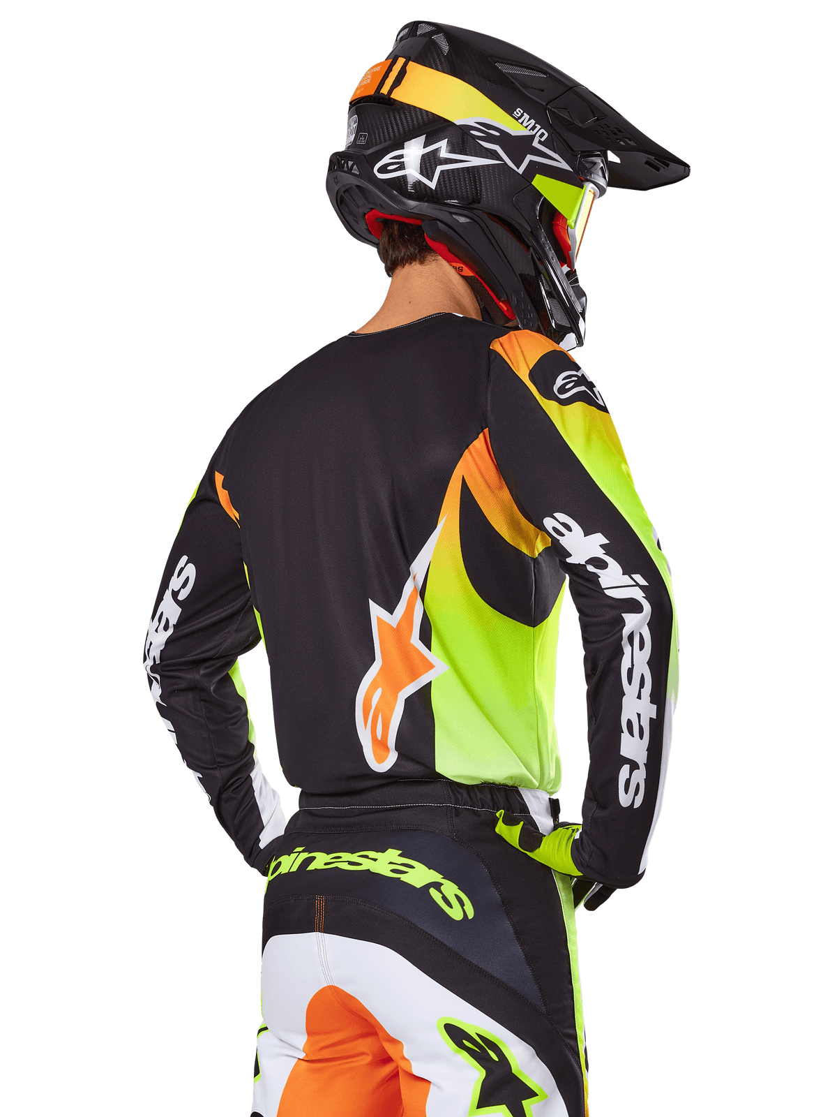 Motocross-Fahrer von hinten im Alpinestars 2025 Fluid Wurx Ausrüstungsset, schwarzes Trikot mit leuchtenden neongelben und orangefarbenen Grafiken, passende Hose mit weißen und orangefarbenen Einsätzen, schwarzer Helm mit Neon-Akzenten, markantes Alpinestars-Branding auf den Ärmeln und am Gesäß.