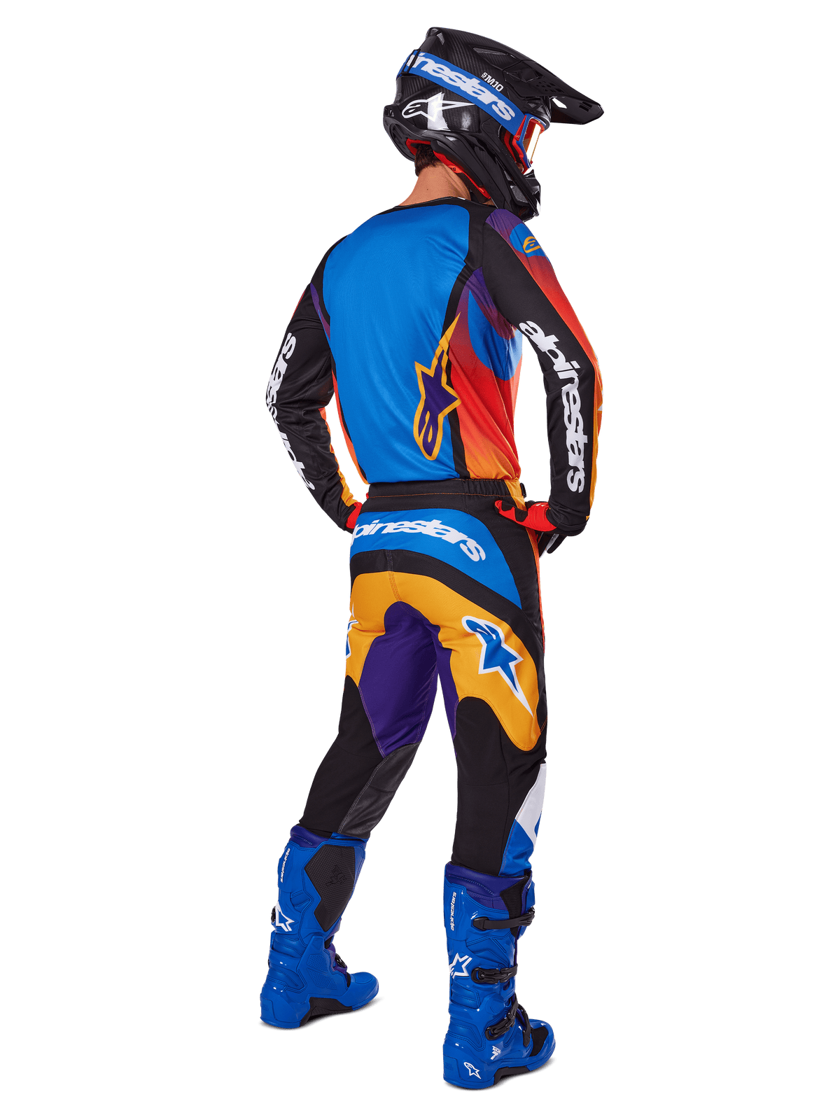 Motocross-Fahrer in der Rückansicht mit Alpinestars 2025 Fluid Wurx Gear Set, mehrfarbiges Trikot mit blauen, orangefarbenen und lila Paneelen, passende Hose mit weißem Alpinestars-Logo auf dem Gesäß, leuchtend blaue Stiefel und schwarzer Helm, koordiniertes Outfit für den Offroad-Rennsport