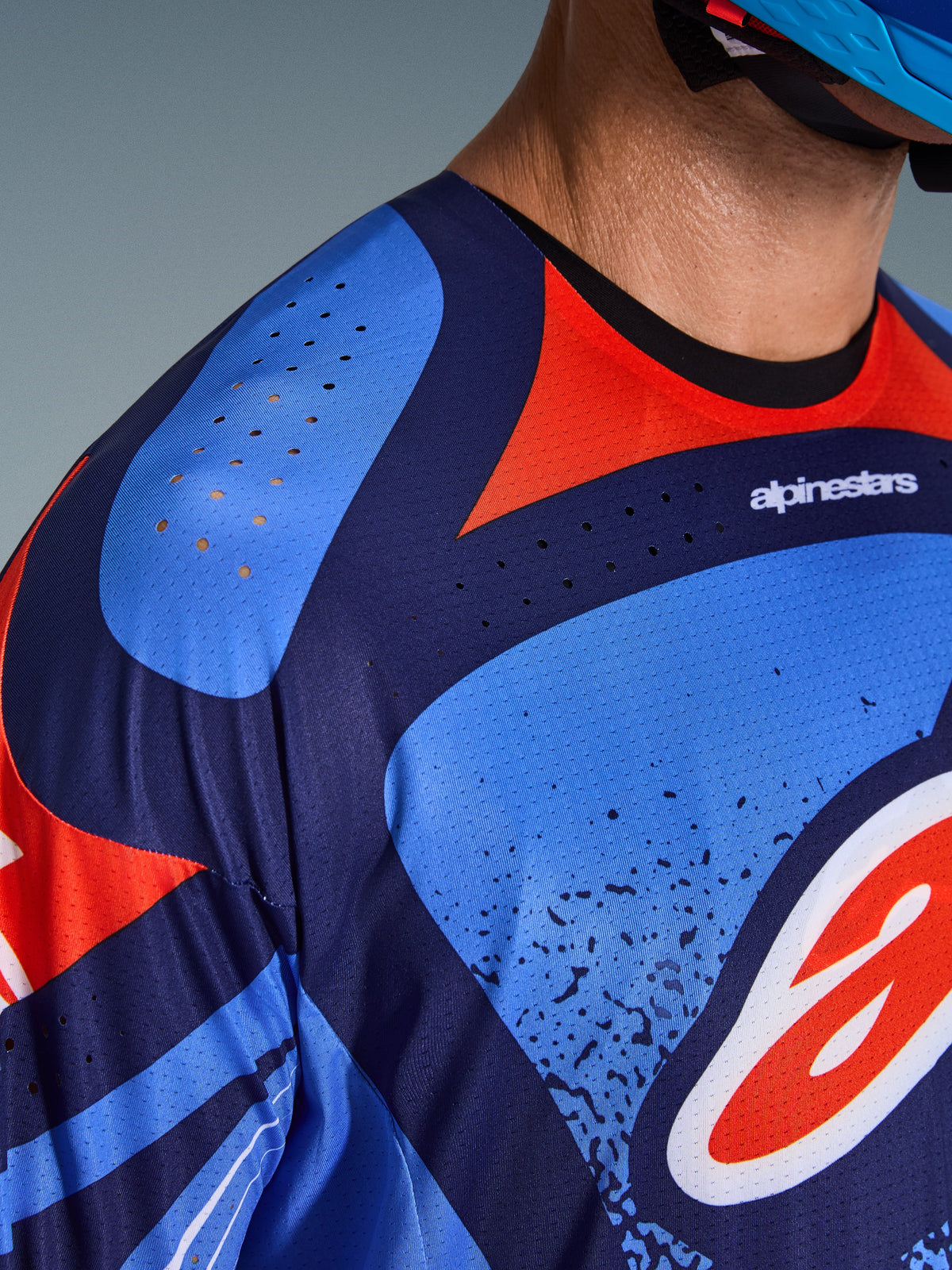 Alpinestars 2026 Techstar Nomur Jersey, Nahaufnahme von Brust- und Schulterbereich, marineblaues und rotes Design mit lasergeschnittenen Belüftungsöffnungen, technisches Poly-Gewebe für Motocross-Performance