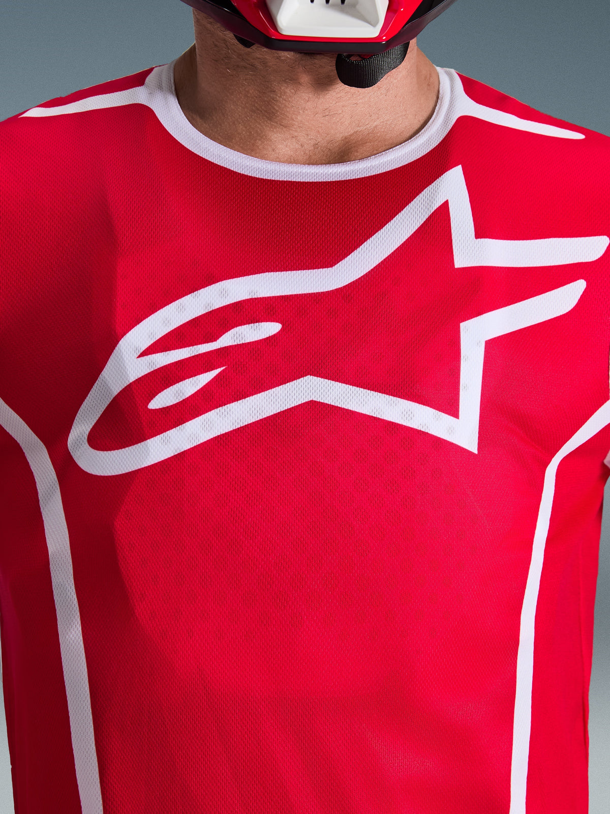 Alpinestars 2026 Fluid Apex Trikot, Rot und Weiß, Nahaufnahme der Brust mit großem weißen Astars-Logo, weißer Sportkragen und feuchtigkeitsableitendes Gewebe für Motocross-Performance