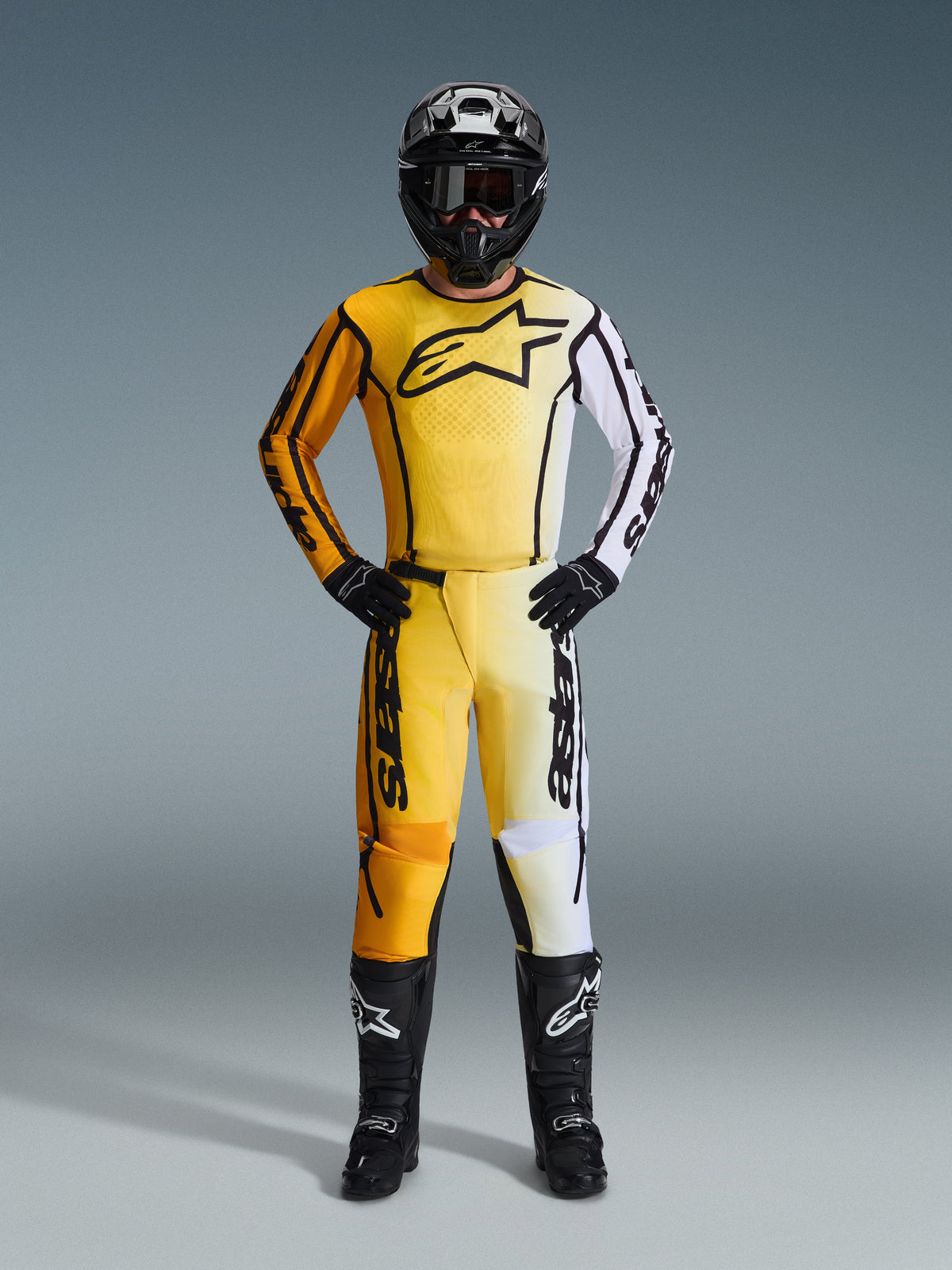 Motocross rider wearing Alpinestars 2026 Fluid Apex Jersey in Yellow and Black, matching pants with white accents, black helmet, black gloves, and black boots, full professional racing gear for motocross