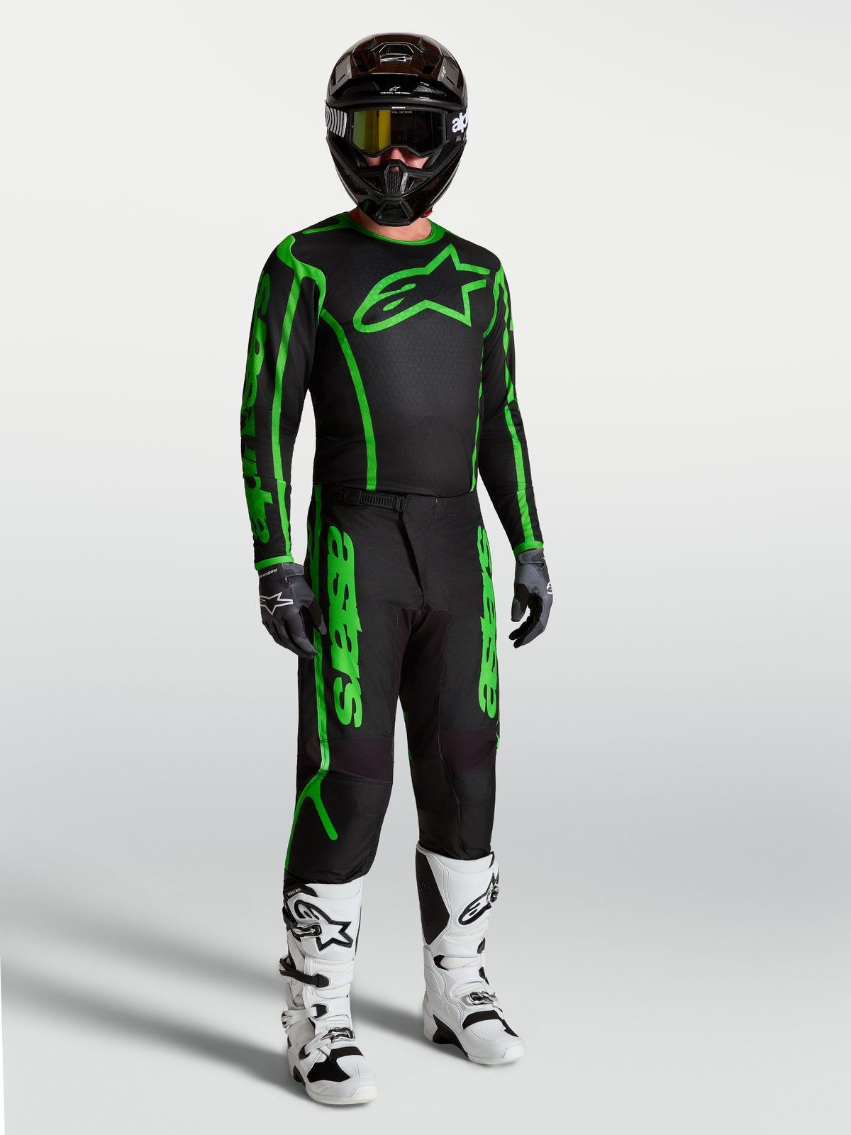 Alpinestars Fluid Apex V2 Hose, Herren-Motocross-Hose, Schwarz und Fluo-Grün, robustes Polygewebe, mit weißen Stiefeln.