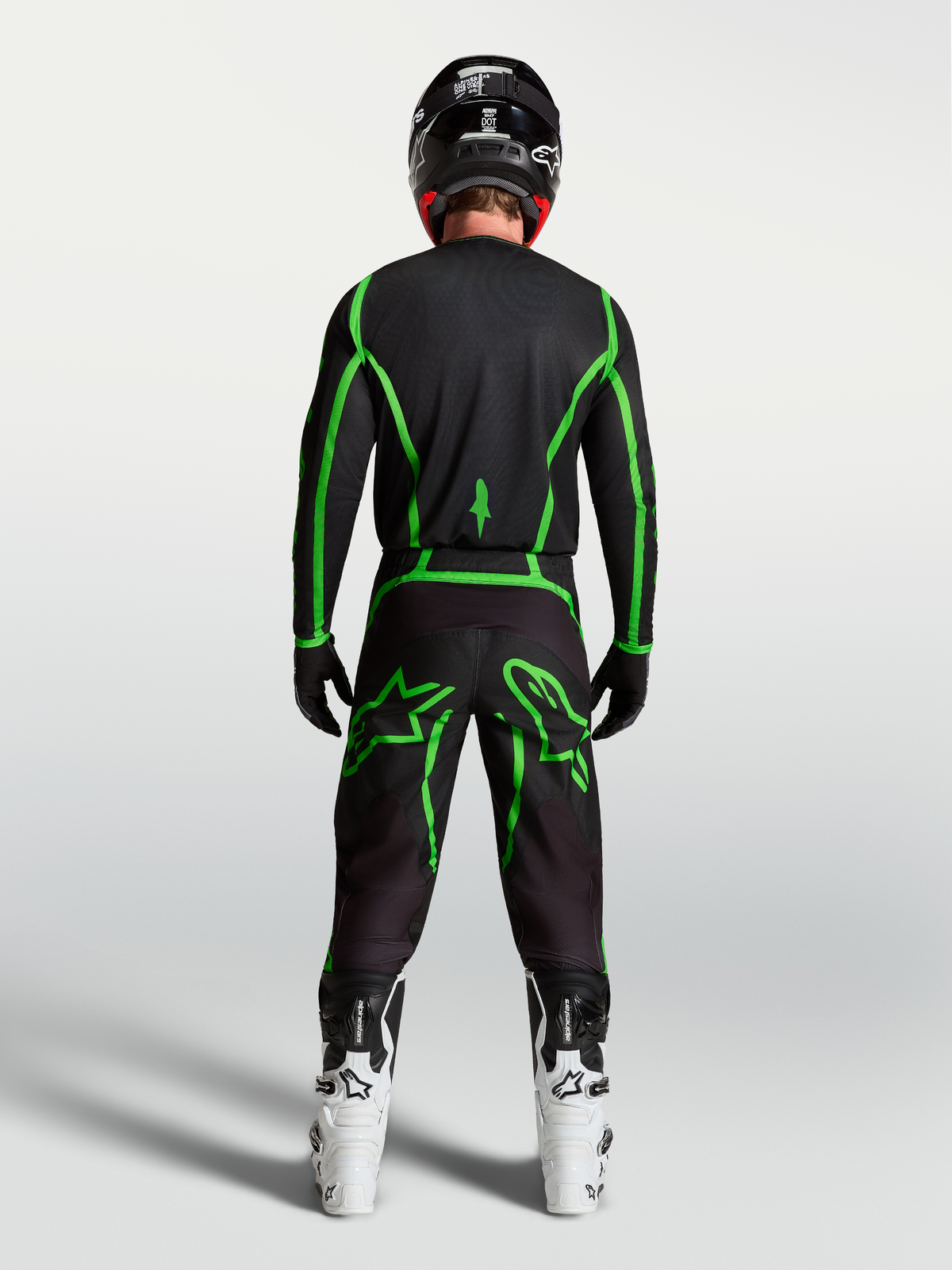 Alpinestars Fluid Apex V2 Hose, Motocross-Hose in Schwarz und Fluo-Grün, Rückansicht am Fahrer mit weißen Motocross-Stiefeln.