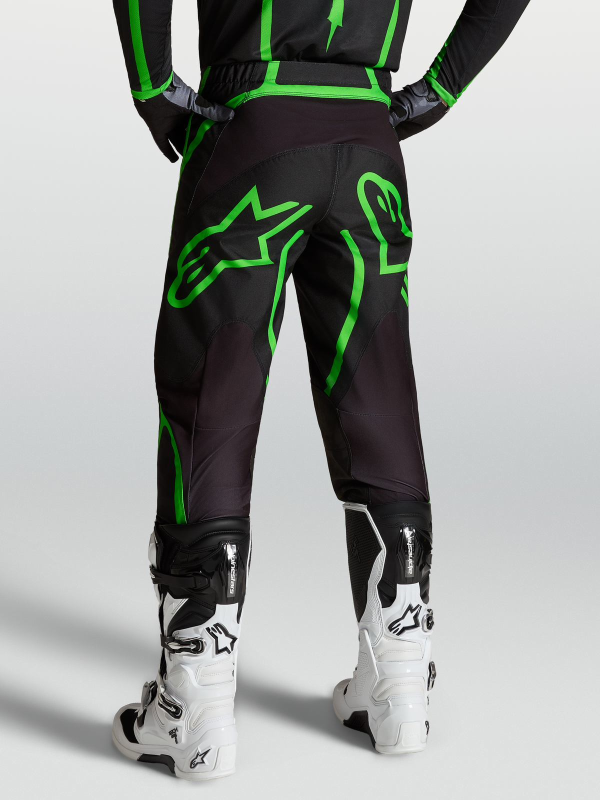 Alpinestars Fluid Apex V2 Hose, Motocross- und Offroad-Hose für Herren, Schwarz und Fluogrün, Rückansicht am Model mit weißen Tech 7 Stiefeln